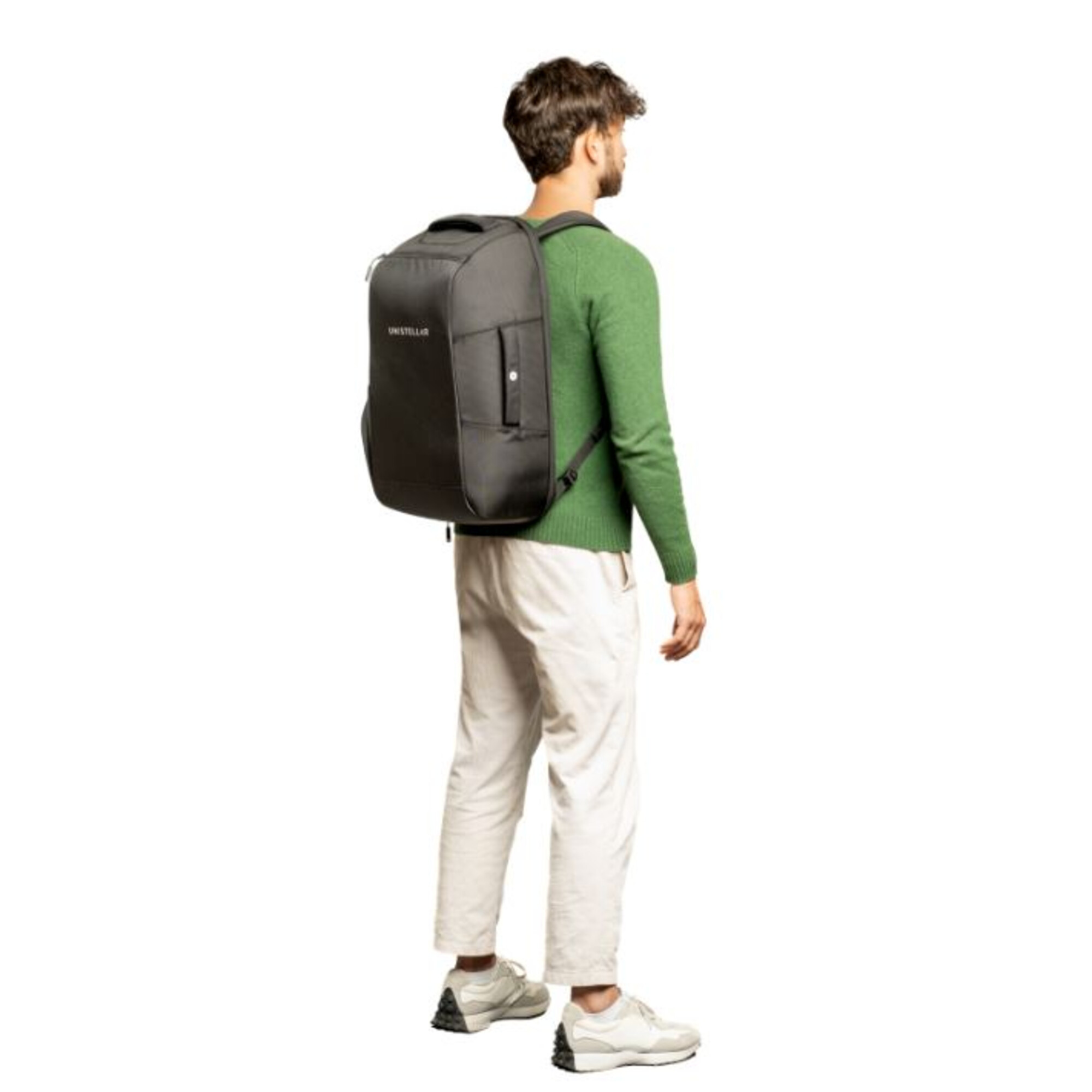 Mann mit schwarzem Rucksack, grünem Pullover und heller Hose, von hinten gesehen.
