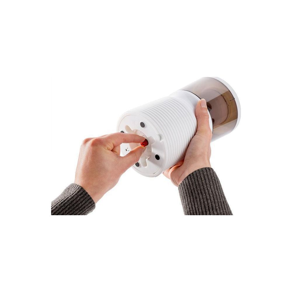 Eine Hand mit einem roten Stift fügt ihn in einen weißen Spitzer ein.
