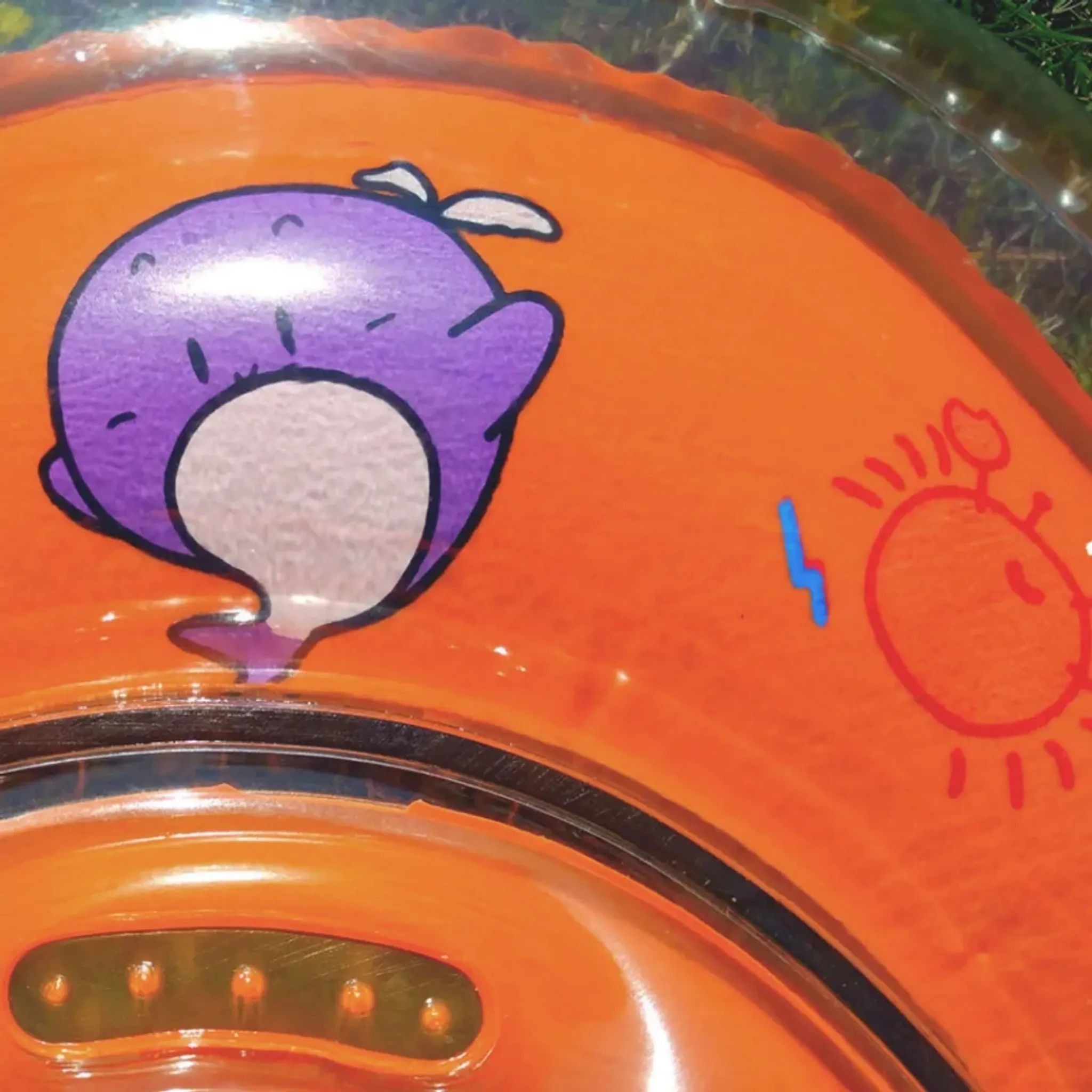 Orange aufblasbarer Ring mit violetter Wal- und roter Sonne.