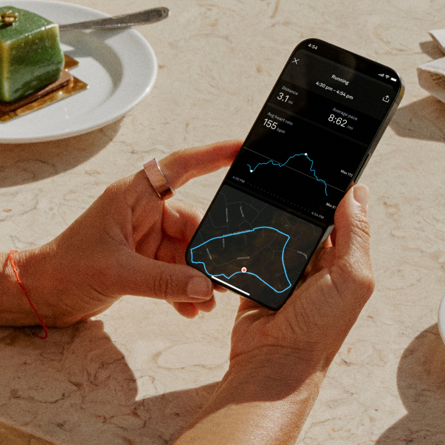 Eine Person hält ein Smartphone, das Laufdaten wie Distanz, Herzfrequenz und Pace anzeigt.