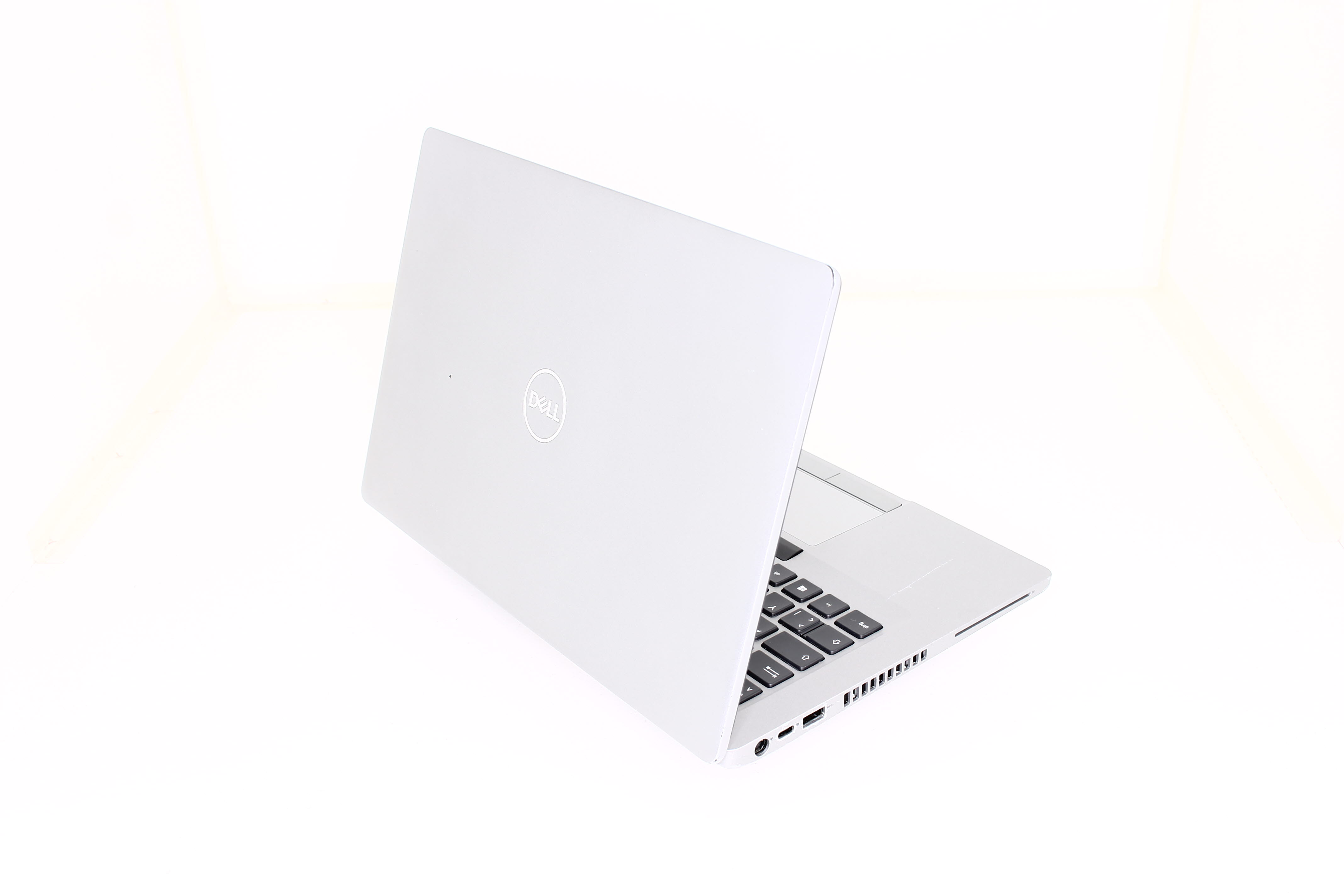 Ein silberner Dell Laptop mit Tastatur und Touchpad ist auf weißem Hintergrund zu sehen.