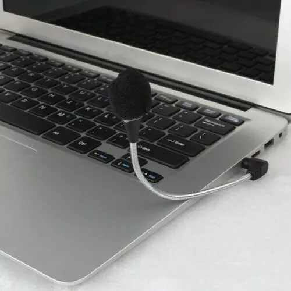 Ein kleines schwarzes Mikrofon mit flexiblem Arm ist an einer silbernen Laptop-Tastatur befestigt.