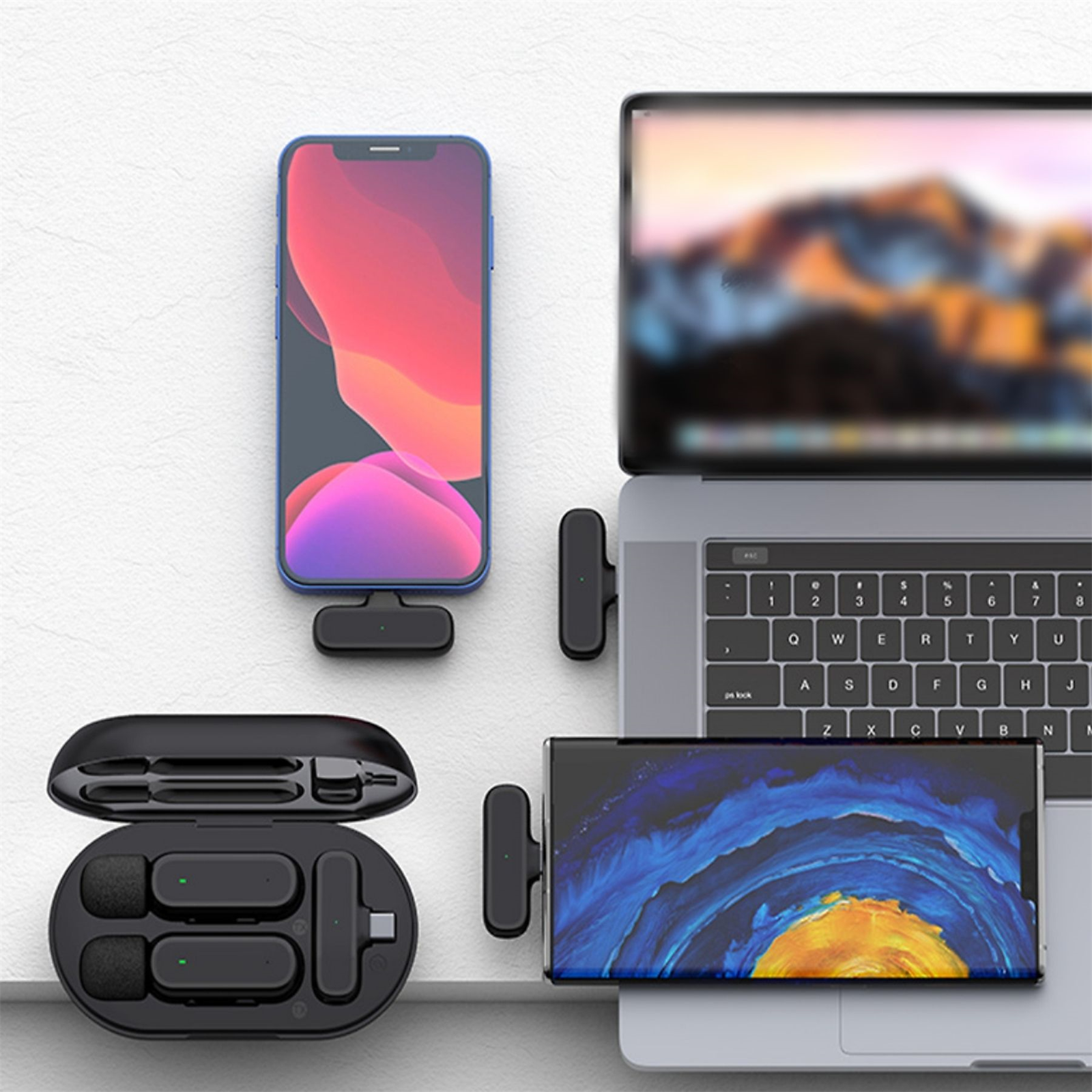 Ein Smartphone, Laptop und ein Ladeetui mit Zubehör auf einer weißen Oberfläche.