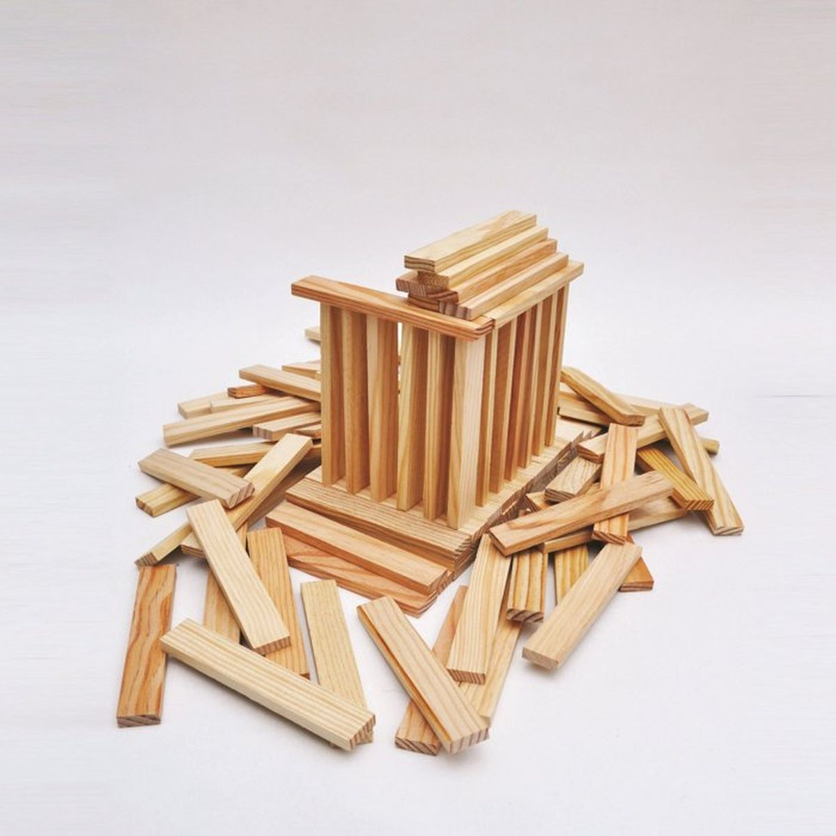 Blocchi di legno impilati formano una struttura, sparsi su una superficie bianca.
