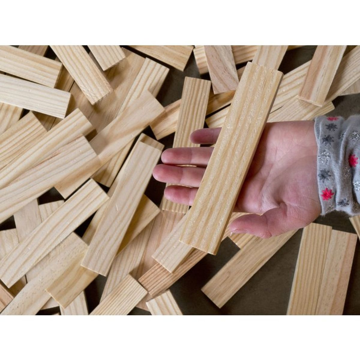 Una mano tiene un blocco di legno su una pila di blocchi. Venatura del legno dettagliata.