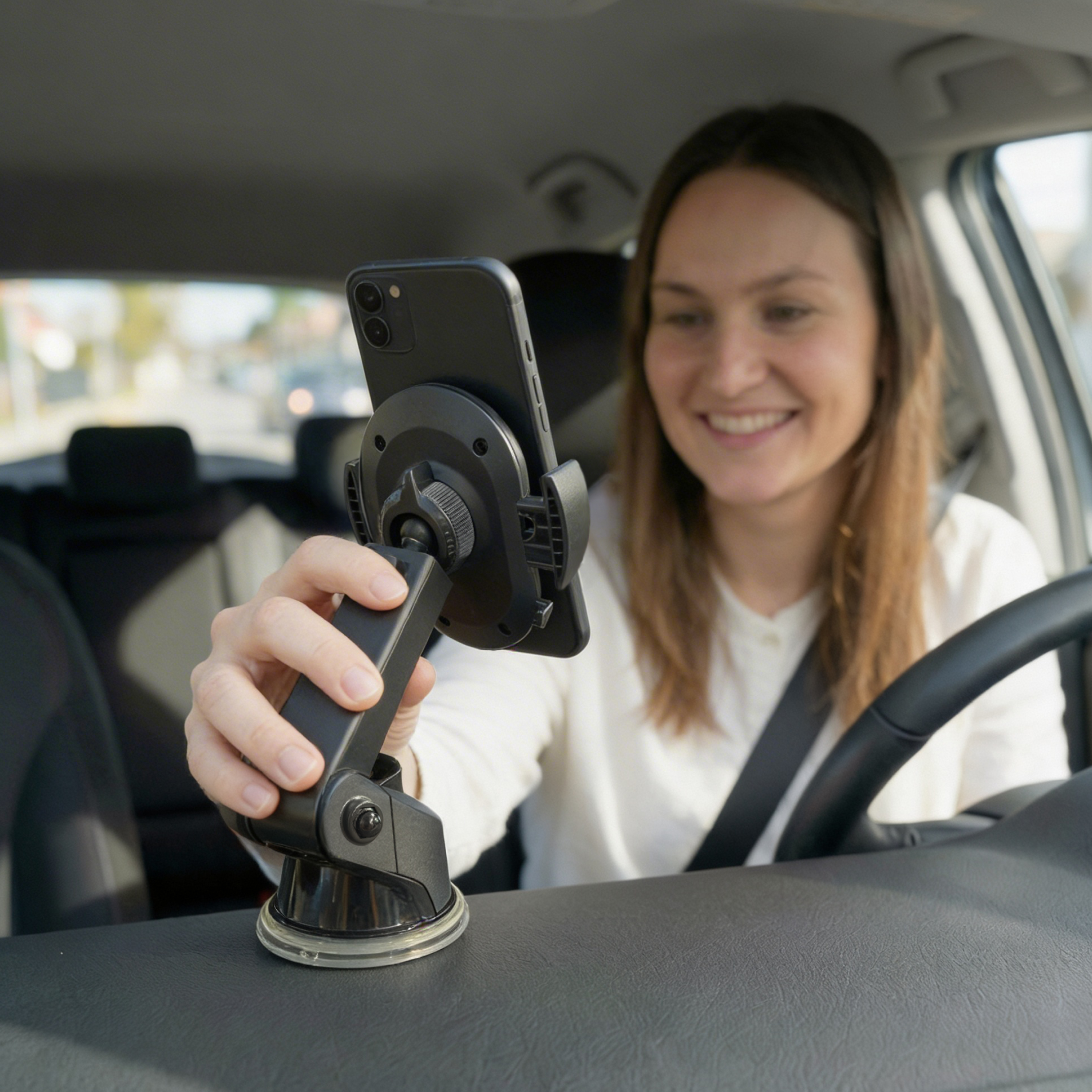 Eine Frau im Auto stellt ein Handy in einer Halterung ein. Sie lächelt.