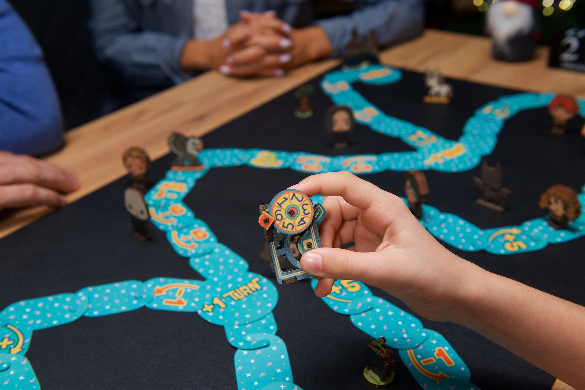 Eine Hand hält ein Spielteil mit Zahlen auf einem Brettspiel mit Figuren.