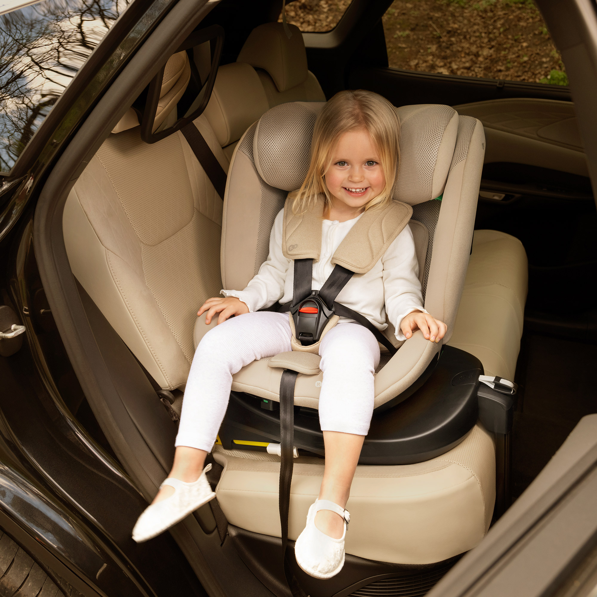 Ein kleines blondes Mädchen sitzt in einem Kindersitz im Auto.