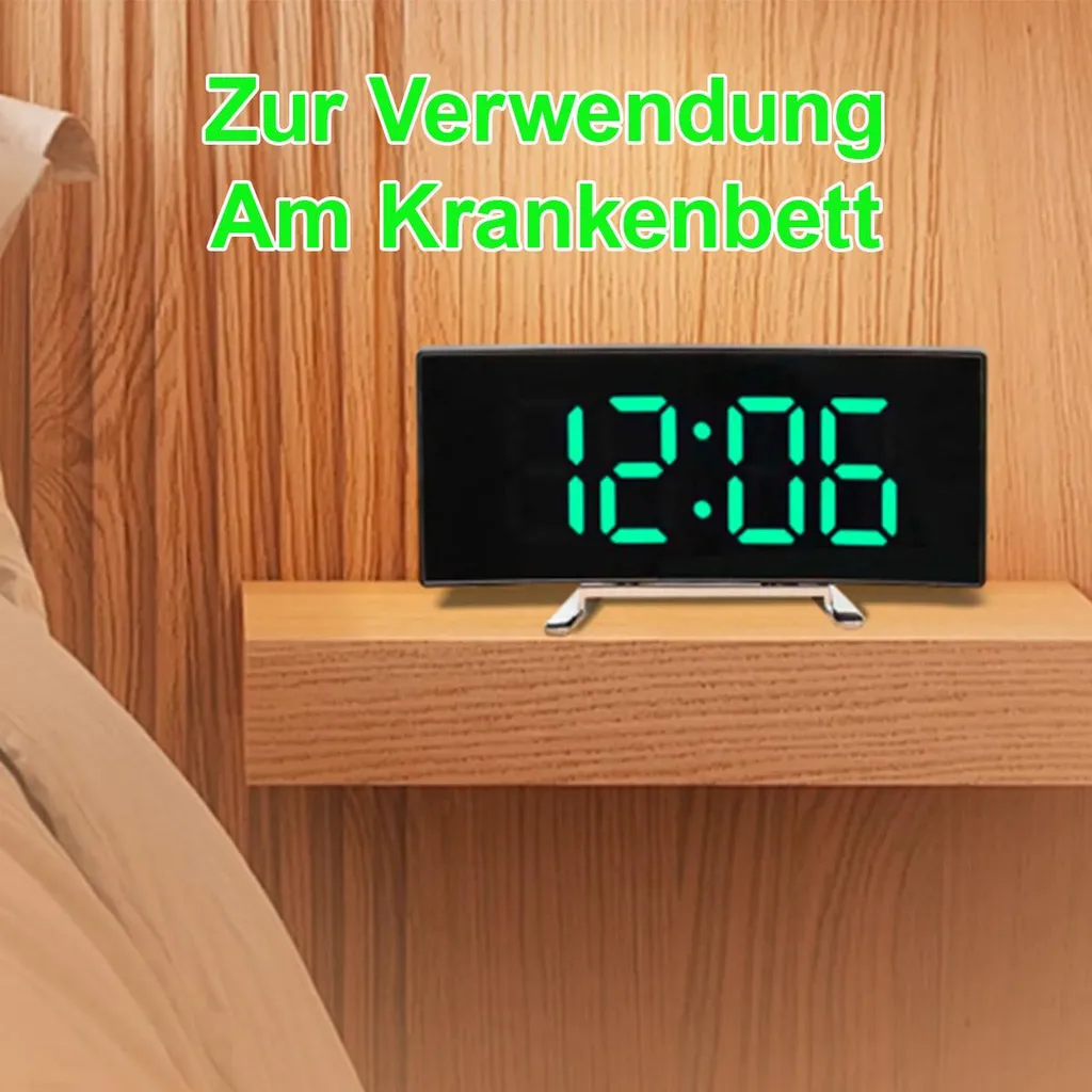 Digitaluhr zeigt 12:06 auf einem Nachttisch neben einem Bett.