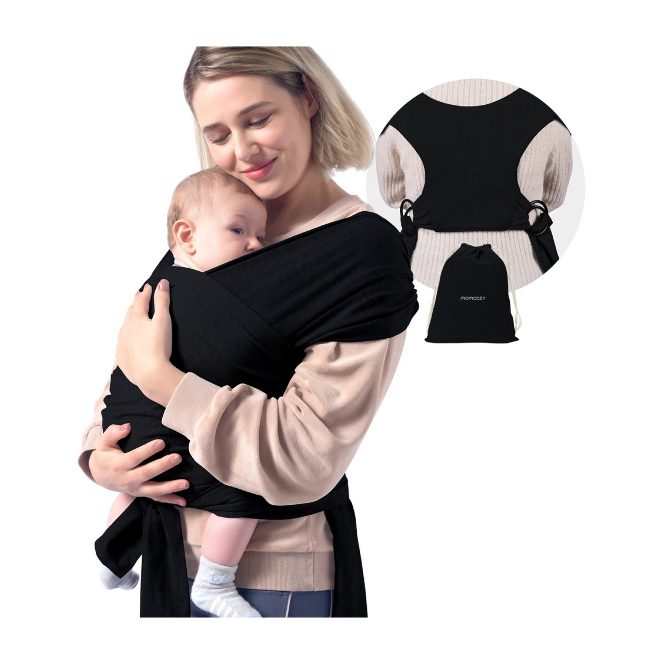 Una donna tiene un bambino in una fascia di stoffa nera. Accanto c'è una fascia arrotolata e una pochette nera.