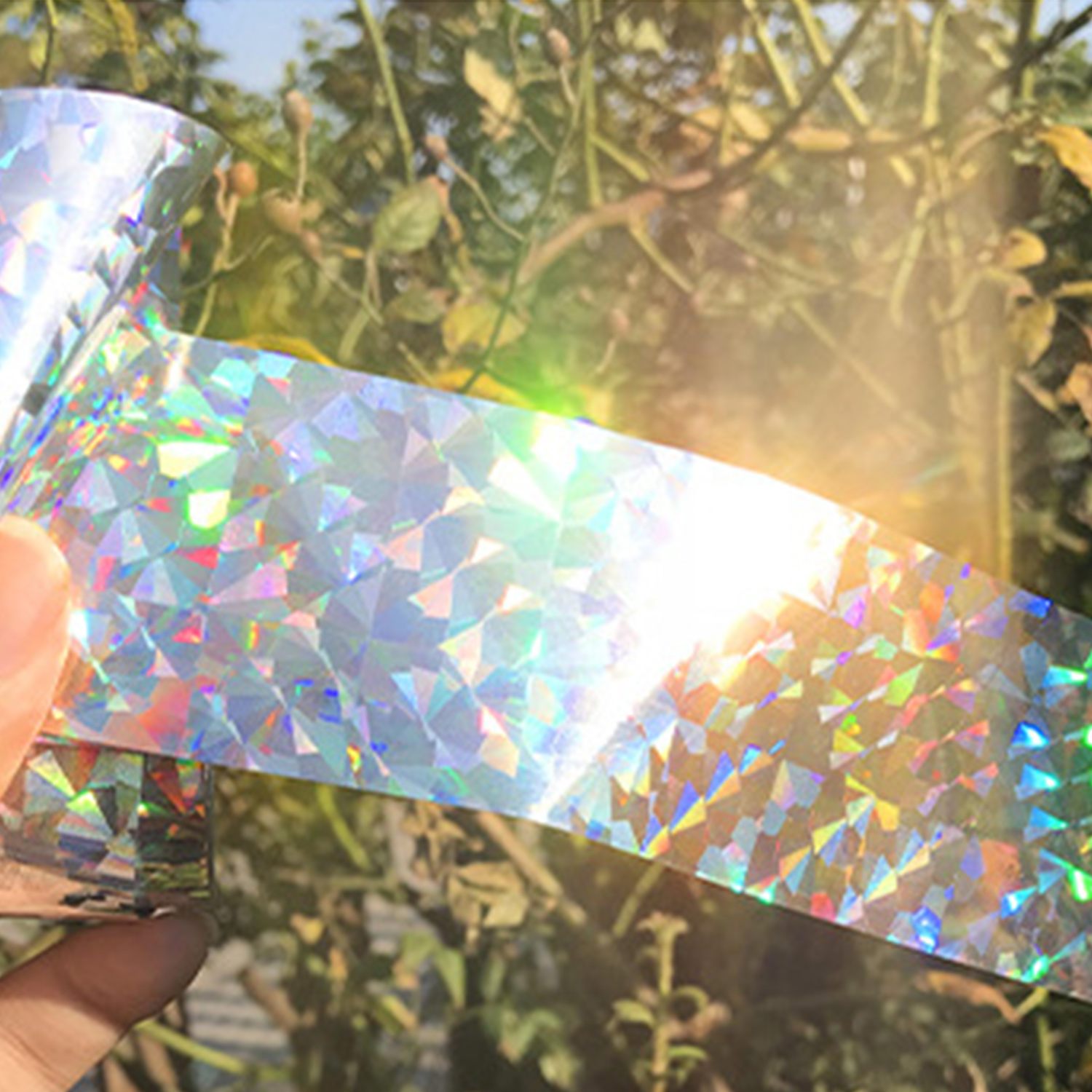 Un ruban holographique brillant à motifs triangulaires est tenu par une main.