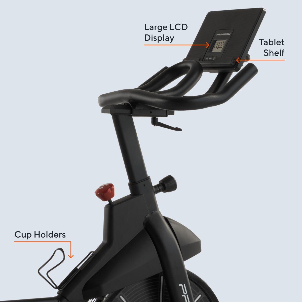 Czarny rower treningowy z wyświetlaczem LCD, półką na tablet i uchwytami na kubki.