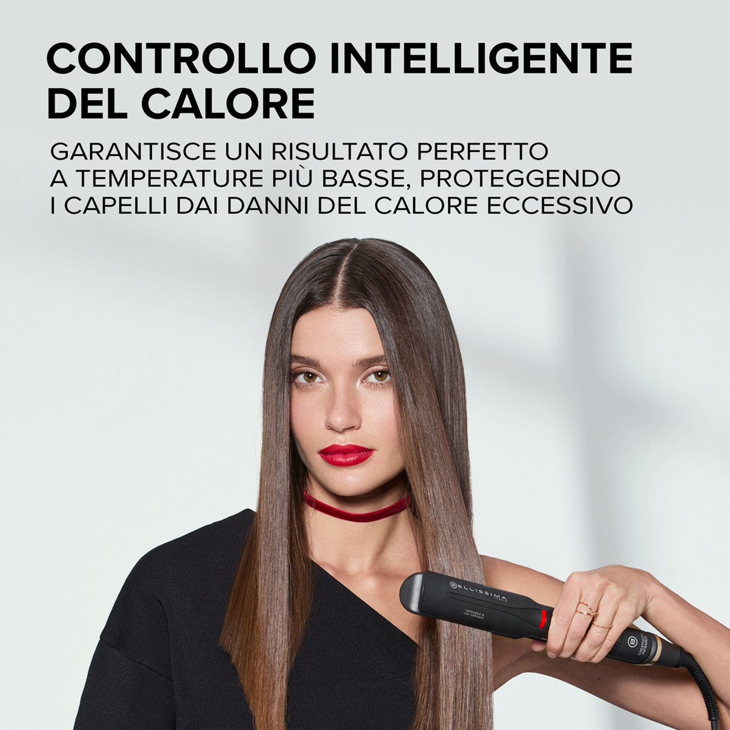 Eine Frau mit langen braunen Haaren hält einen schwarzen Haarglätter.