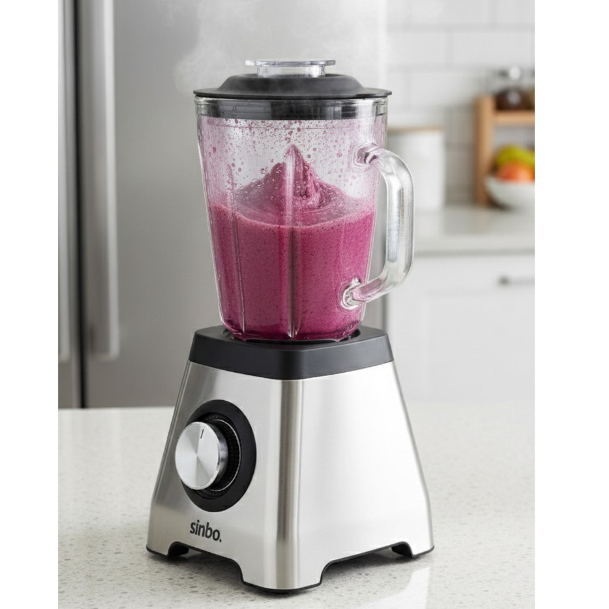 Tezgah üzerinde mor smoothie ve buharı olan gümüş blender.