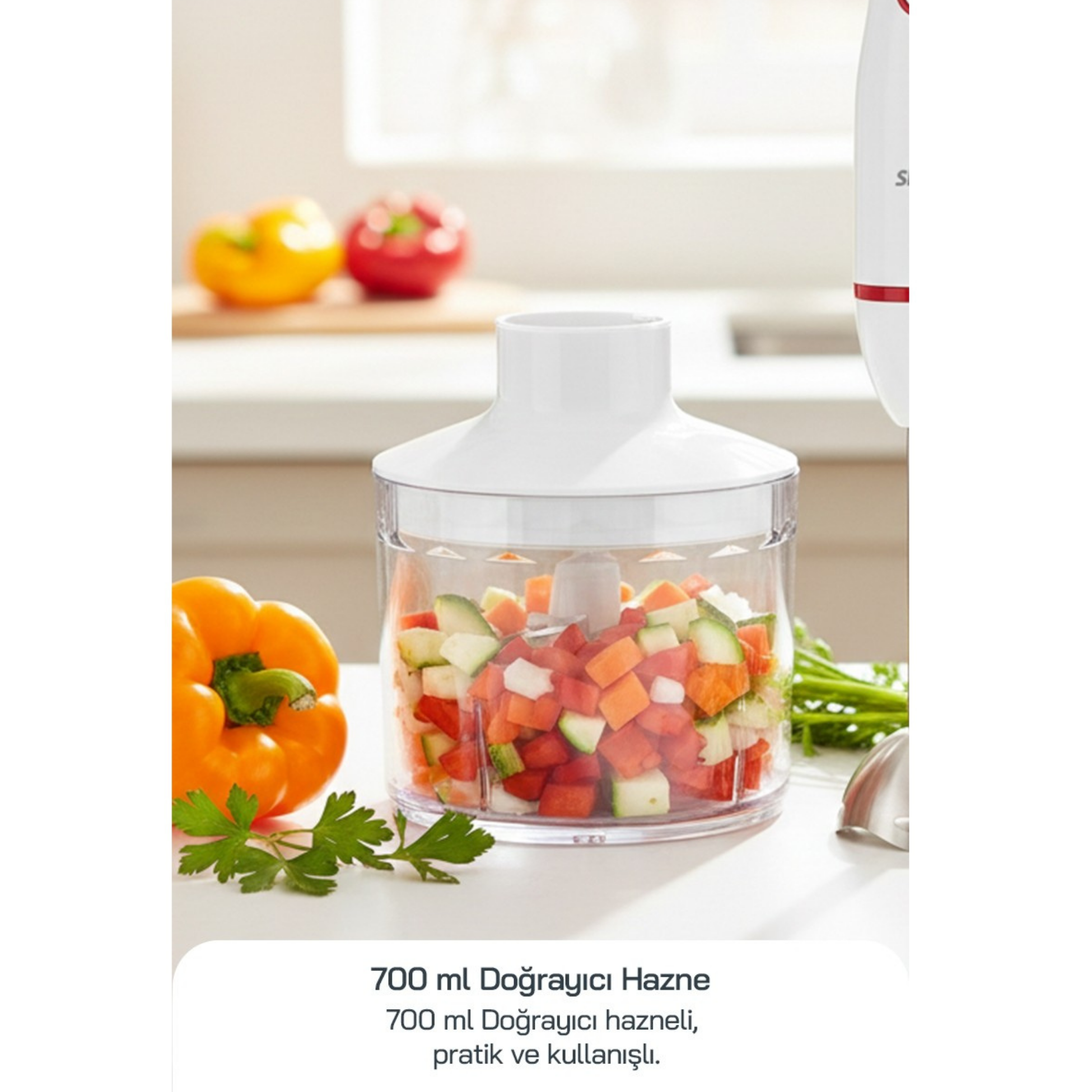 Doğranmış sebzelerle dolu blender kabı, yanında turuncu dolmalık biber.