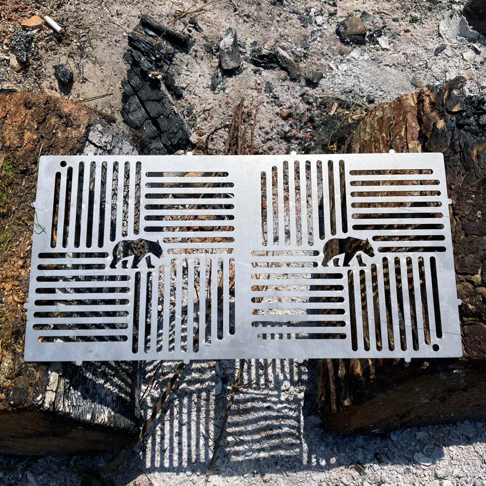 Ayı kesimli metal ızgara, kömürleşmiş kütüklerin ve küllerin üzerinde duruyor.