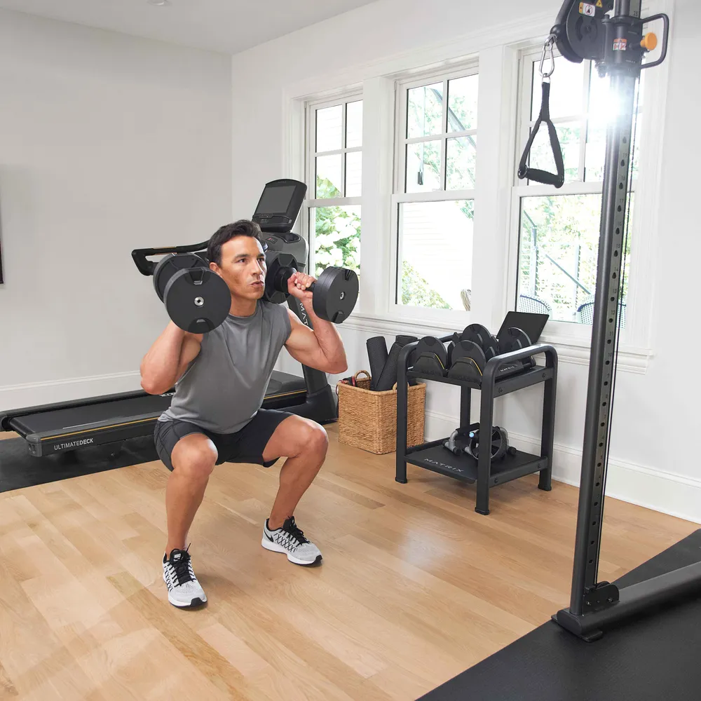 Mann macht Kniebeugen mit Hanteln in einem Fitnessstudio.