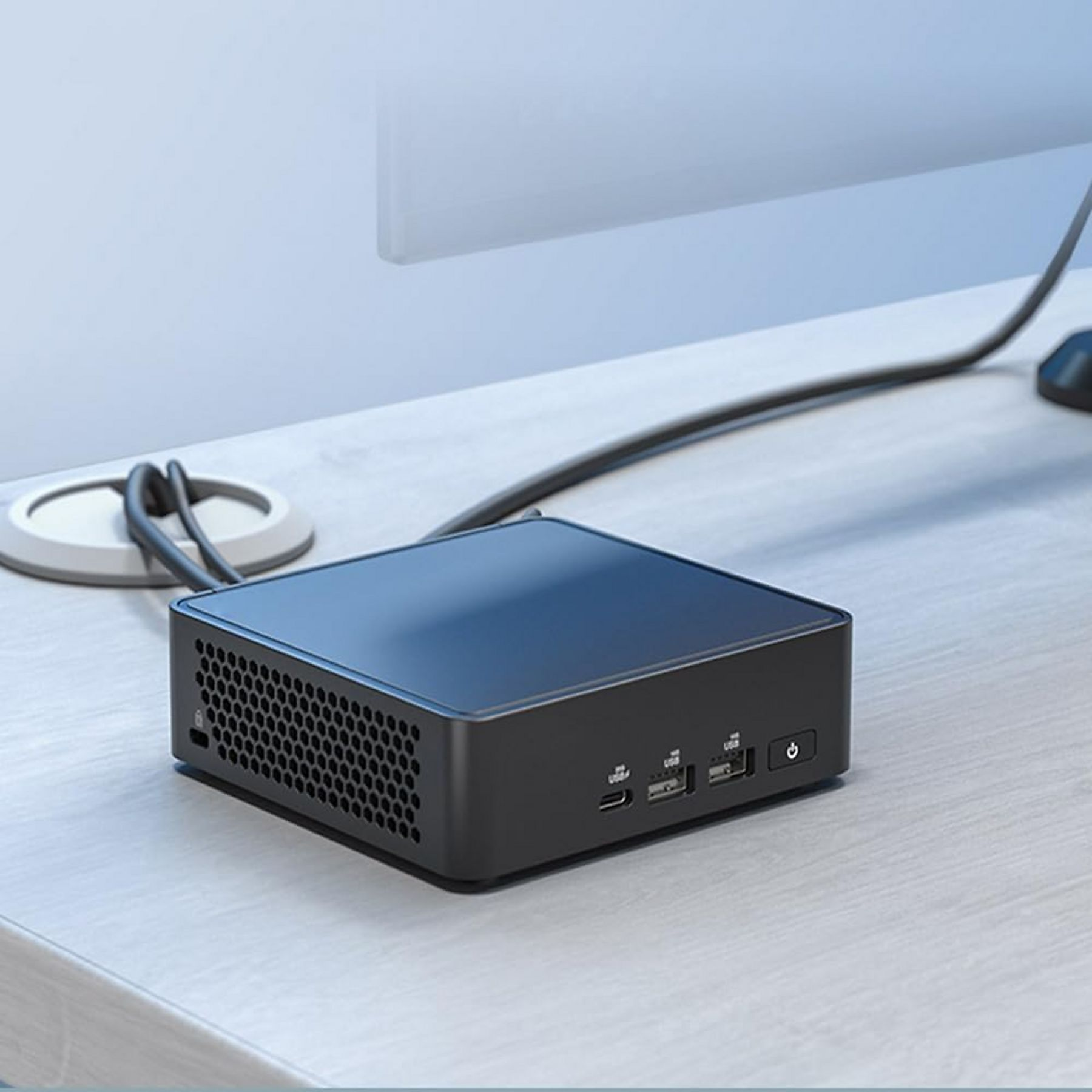 Czarny mini PC z portami USB i przyciskiem zasilania na biurku.