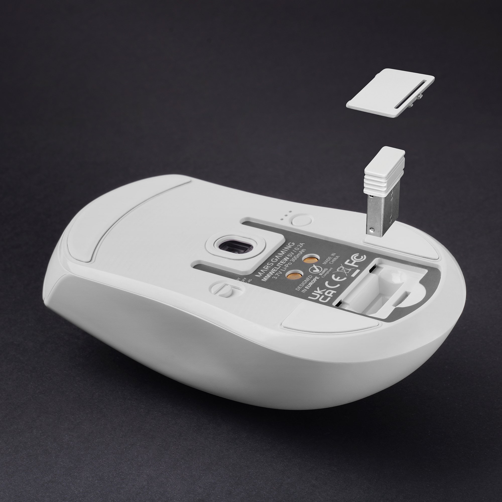 Ratón inalámbrico blanco con dongle USB y cubierta sobre fondo negro.