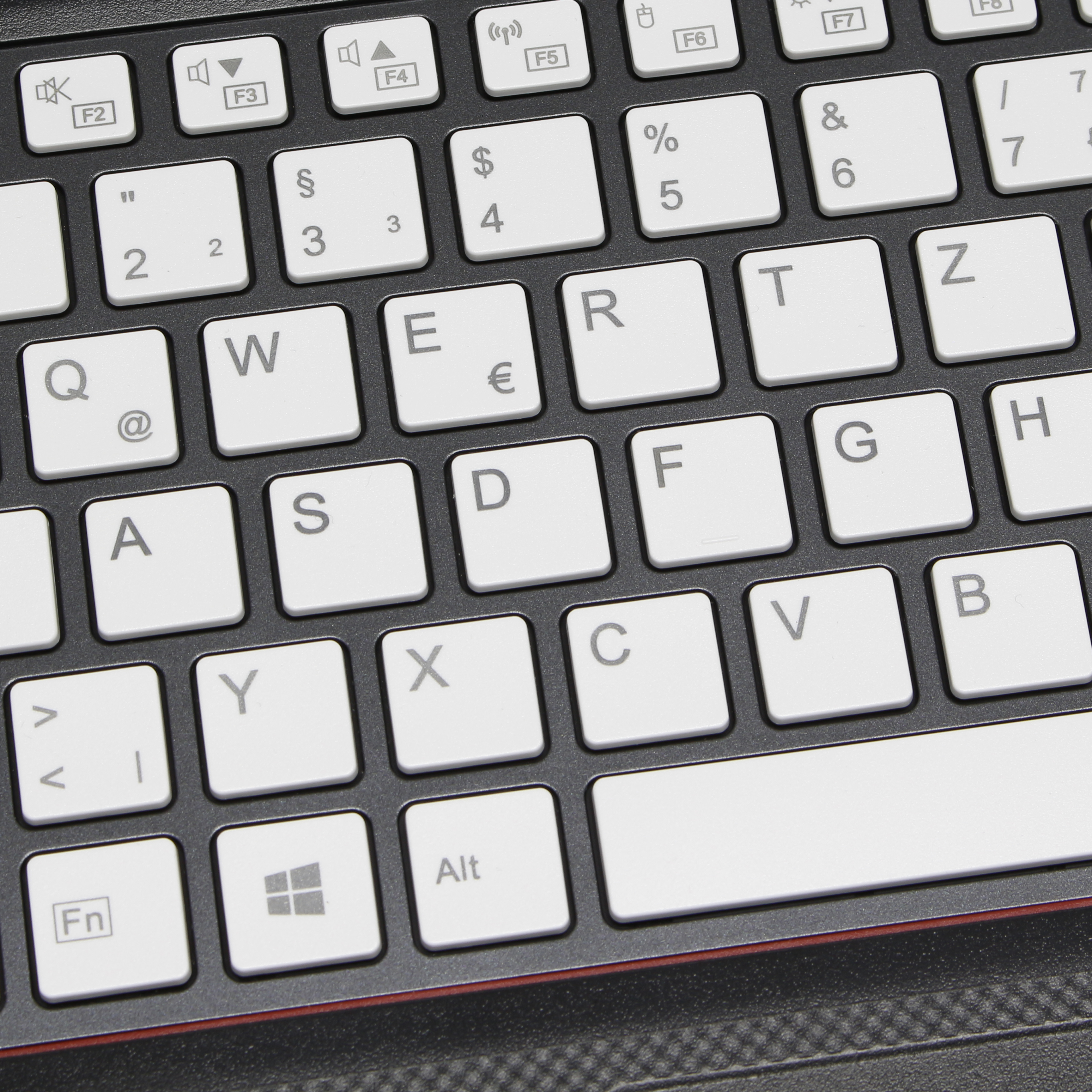 Una vista de cerca de un teclado blanco con teclas negras. Las teclas muestran letras y símbolos.