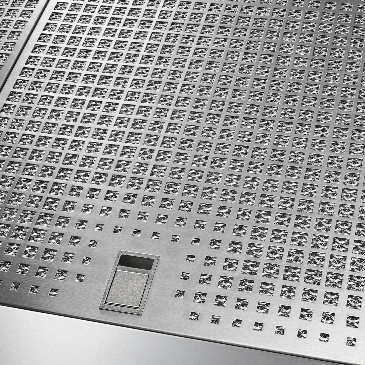 Primer plano de una superficie de metal cepillado con patrón de rejilla y un interruptor.
