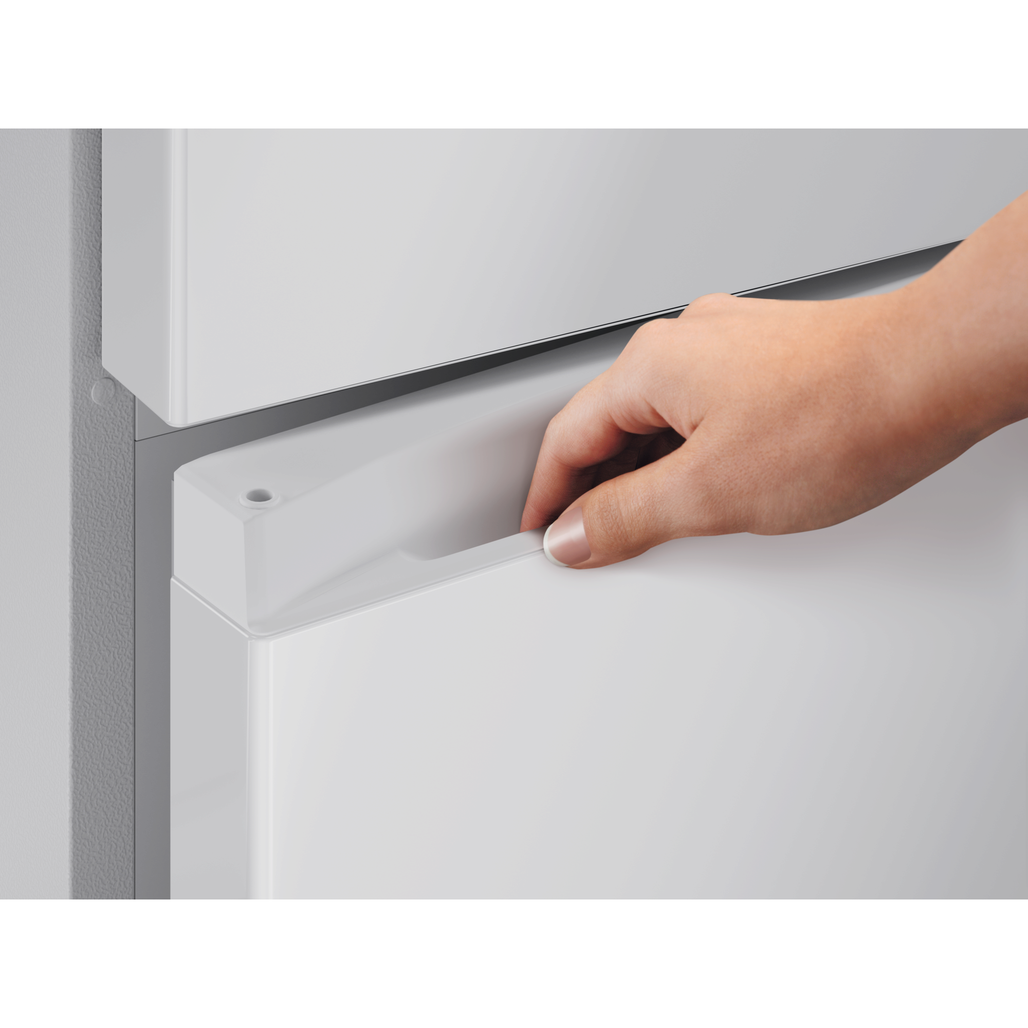 Una mano tira de un cajón blanco de refrigerador por su asa.