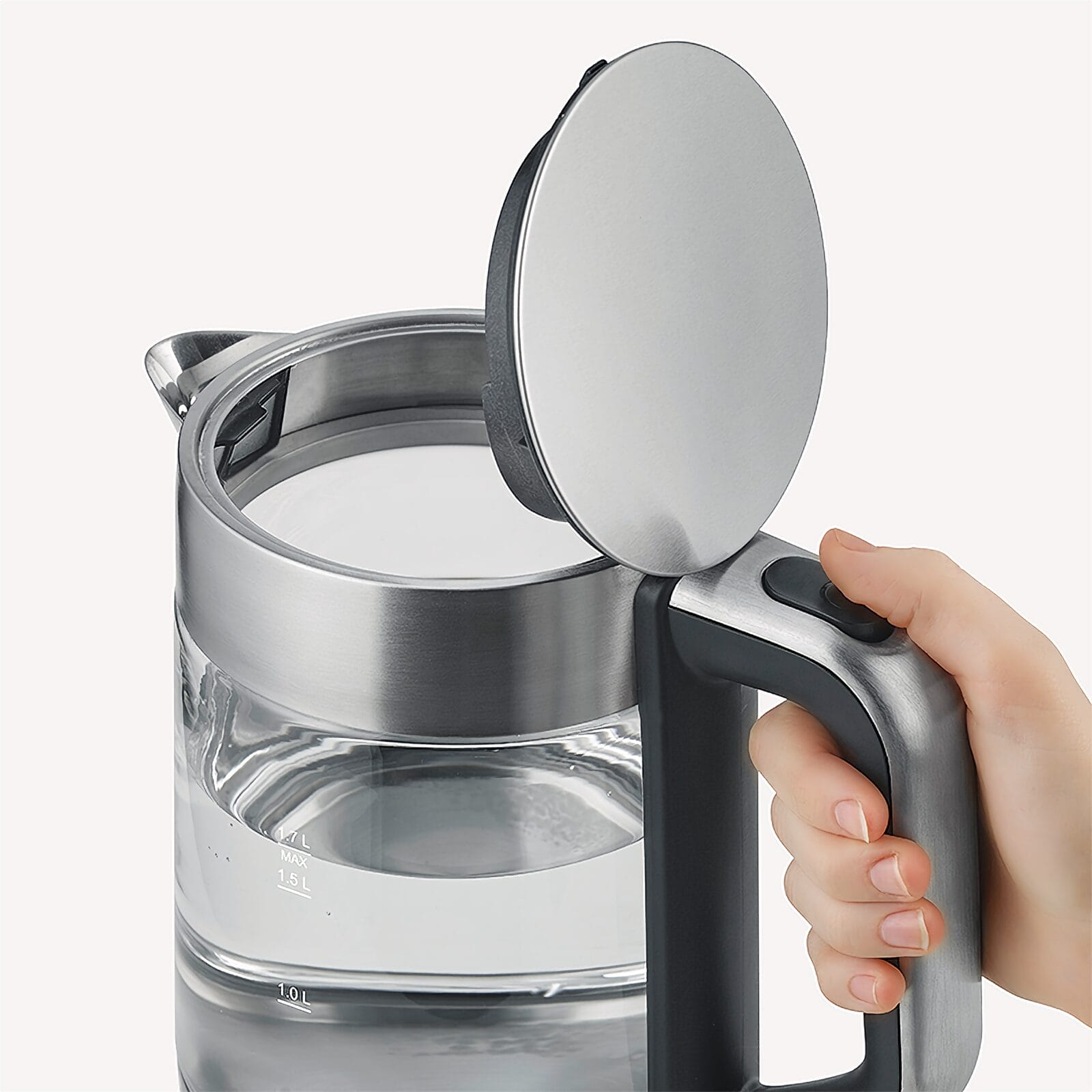 Een hand opent de deksel van een glazen waterkoker.