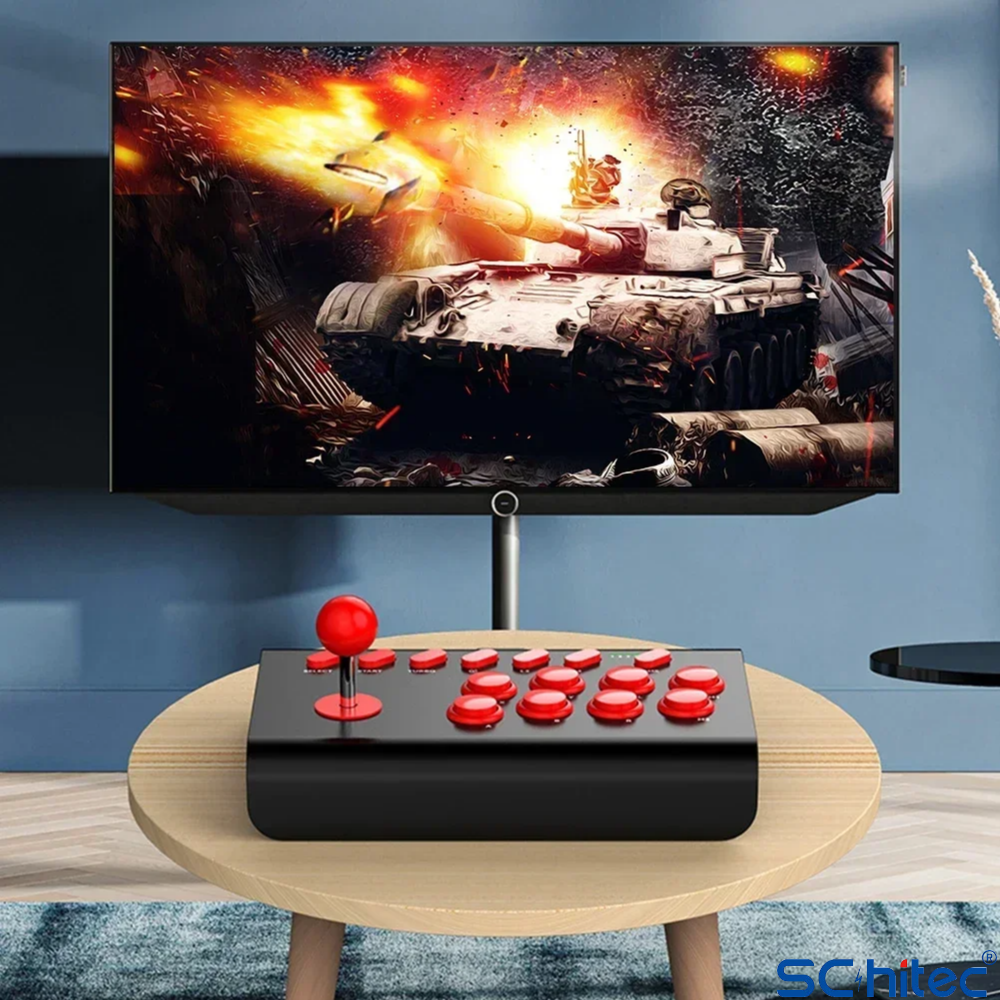 Kırmızı düğmeli siyah bir arcade joystick, tank savaşı gösteren bir TV'nin önündeki ahşap masada duruyor.