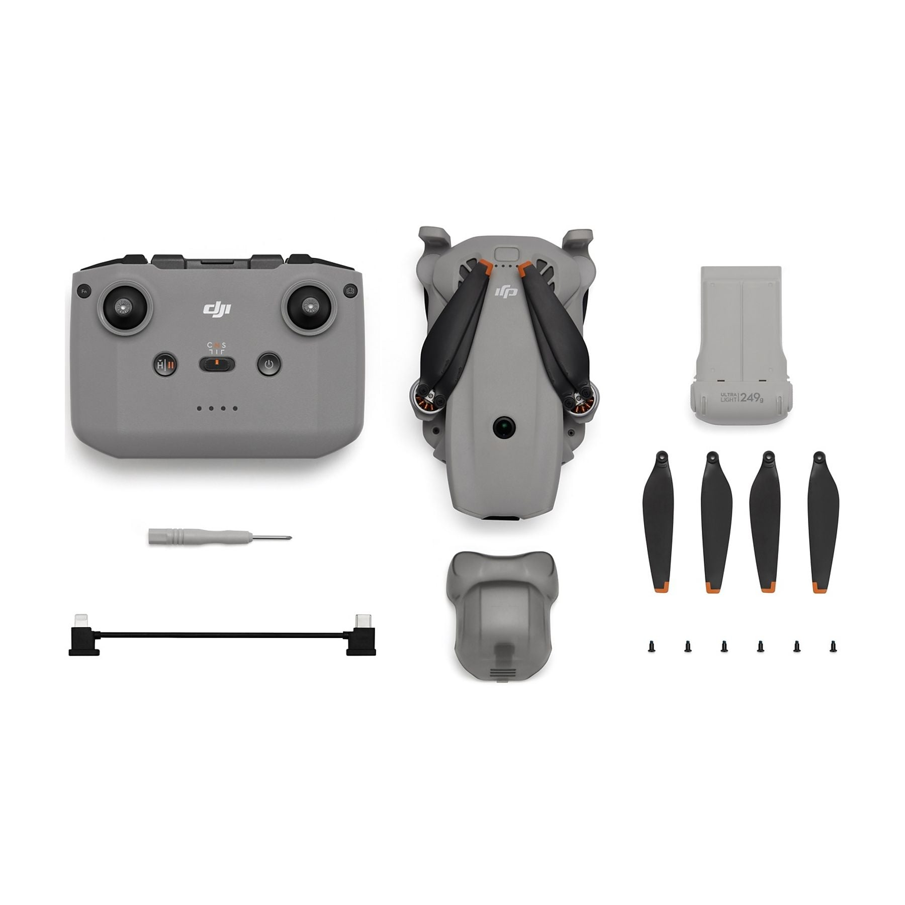 Dron, mando, hélices de repuesto, batería, destornillador y cable sobre fondo blanco.