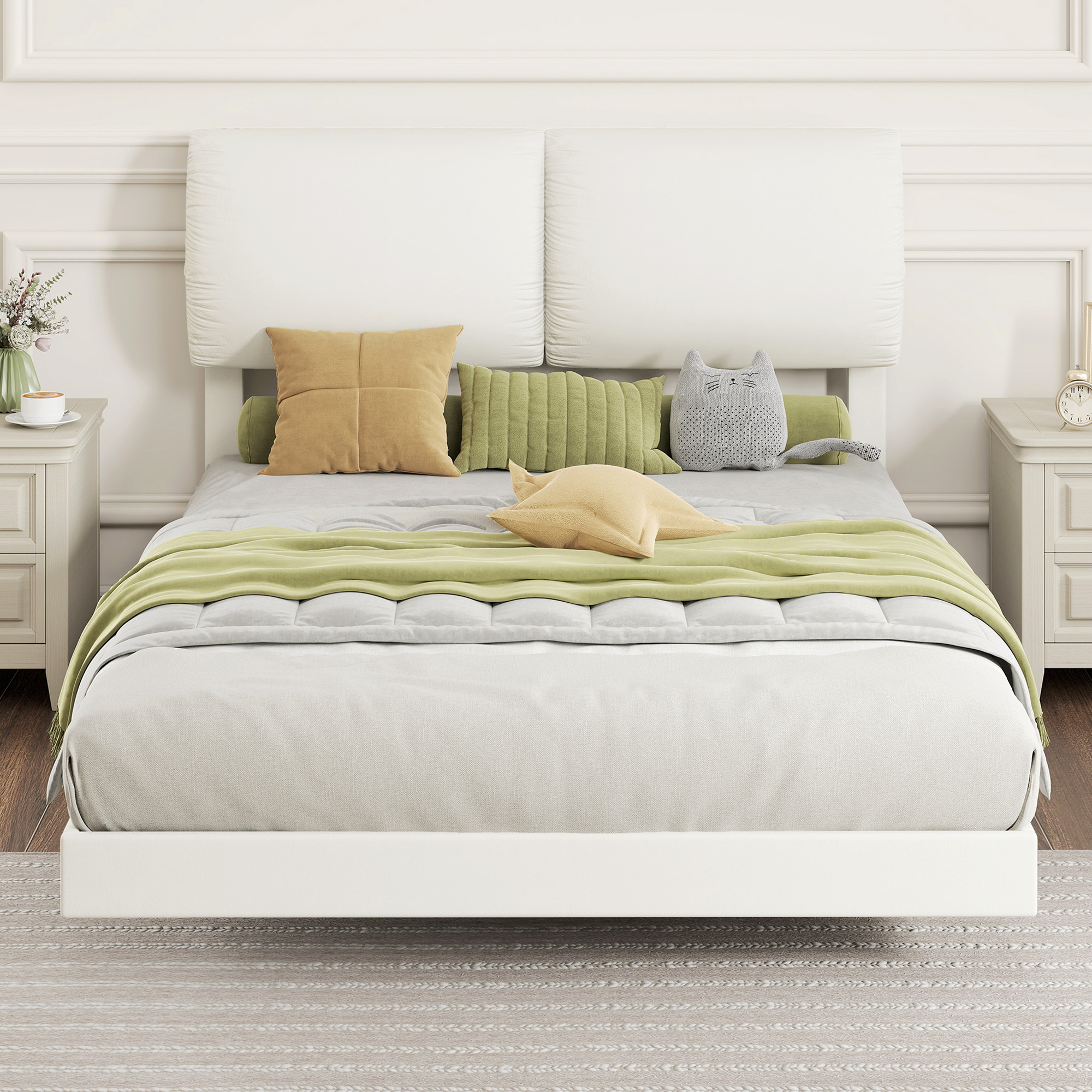 Una cama blanca con cojines y manta verde, flanqueada por mesitas de noche.