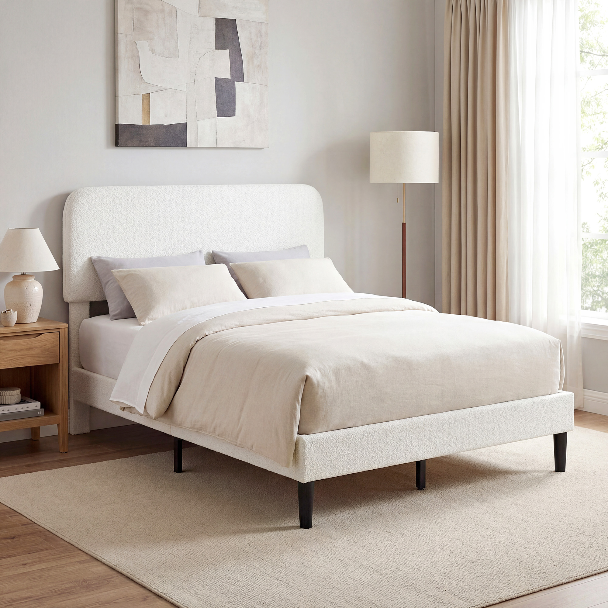 Una cama blanca de bouclé con ropa de cama beige en un dormitorio luminoso.