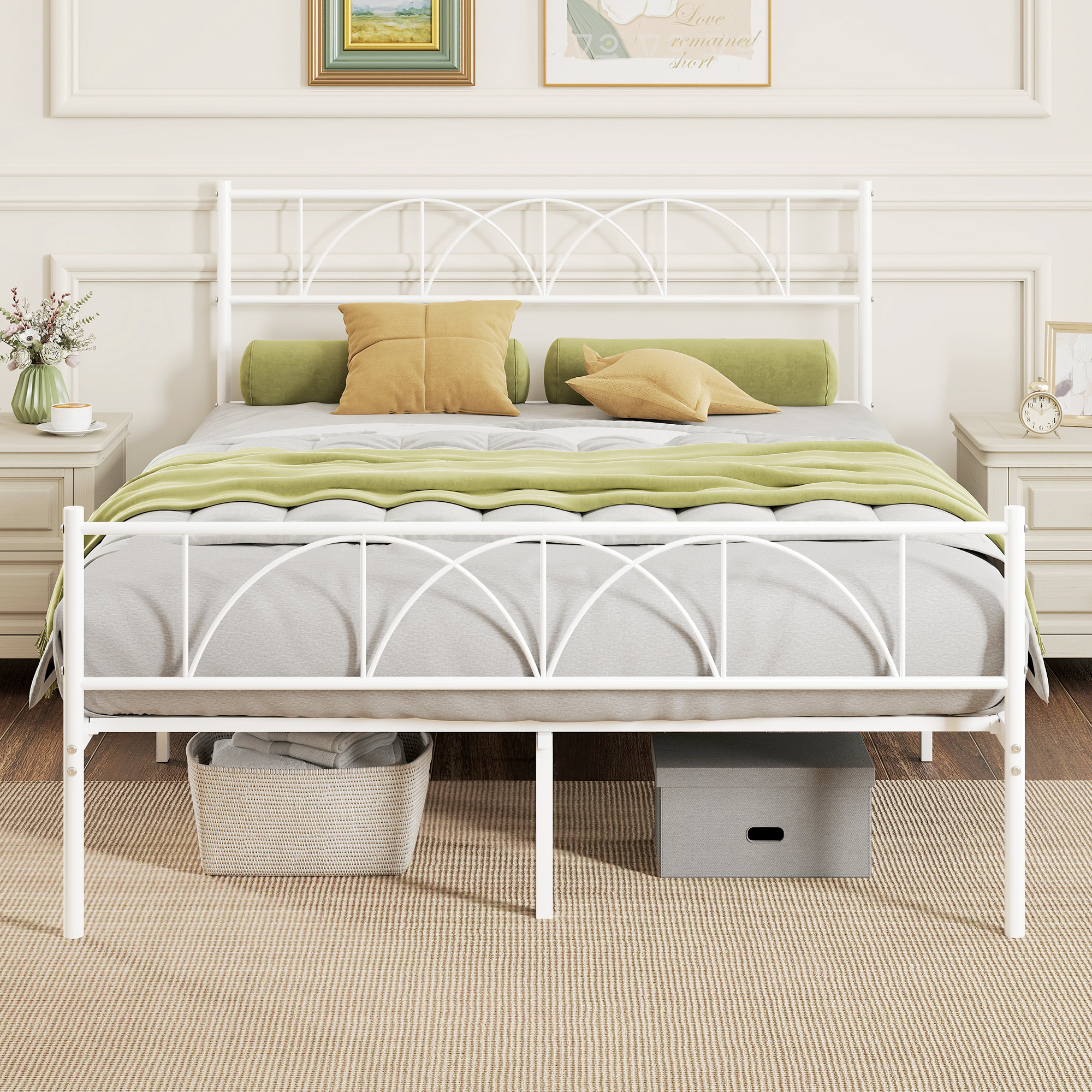 Una cama de metal blanca con cojines y manta, mesitas de noche, cesta y caja.