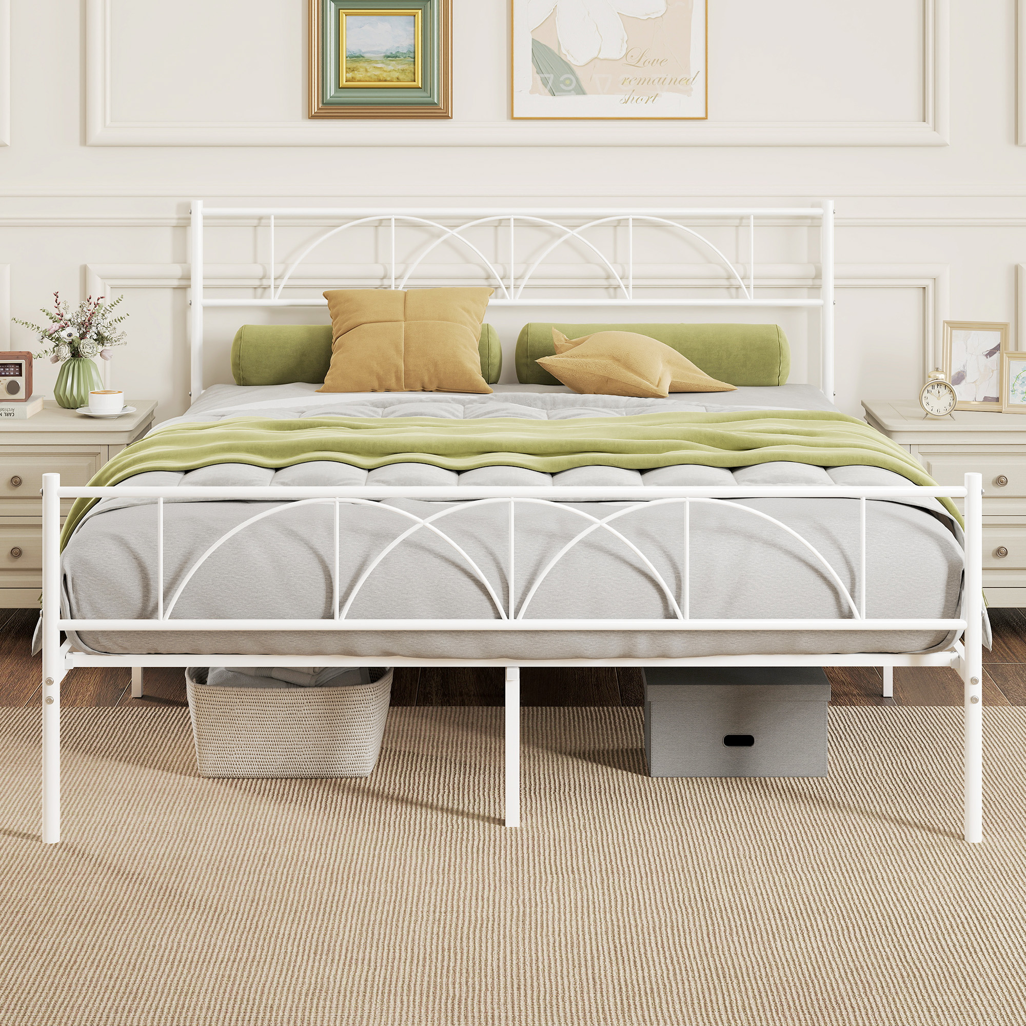 Estructura de cama de metal blanco con almohadas, manta verde y cestas de almacenaje debajo.