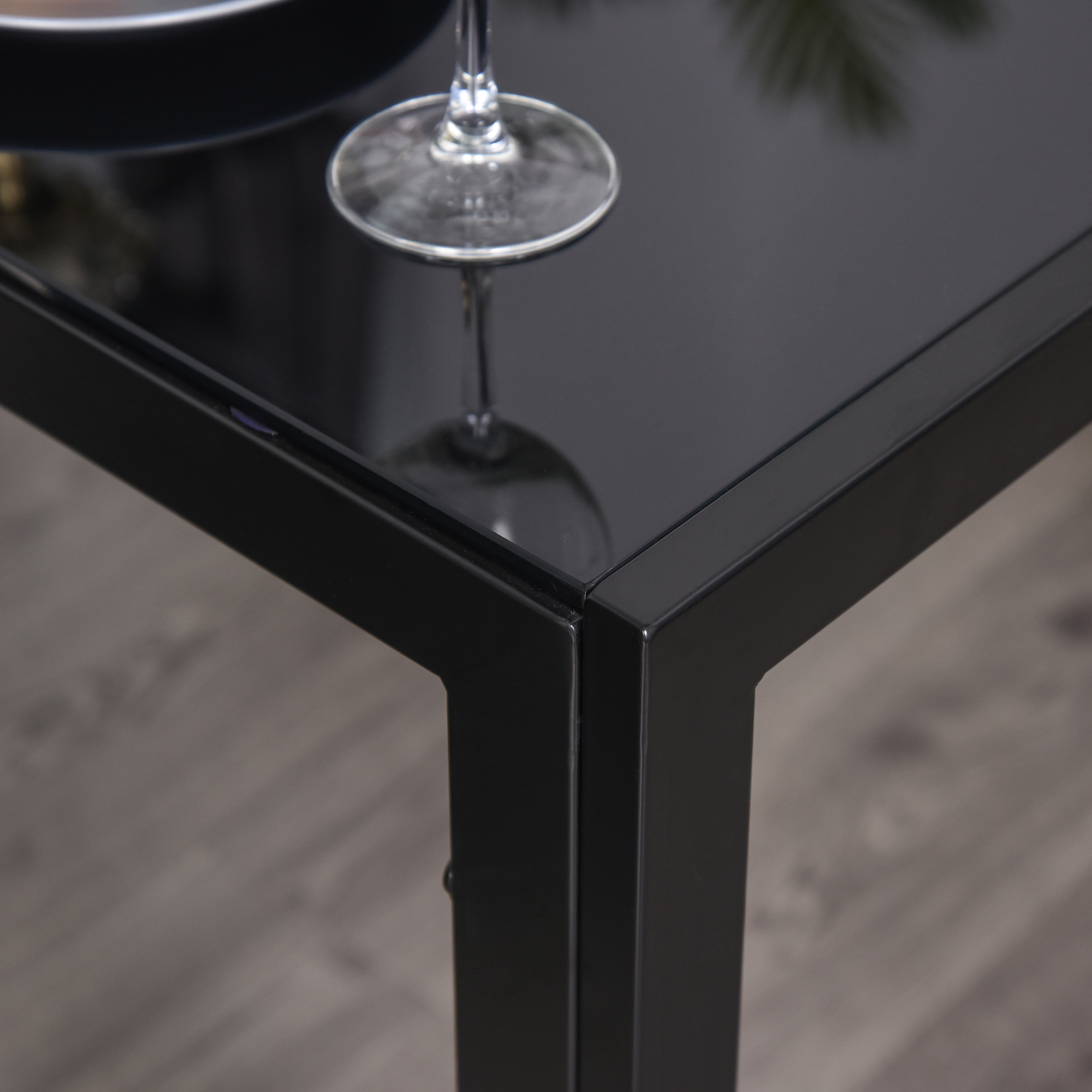 Una copa de vino descansa sobre una mesa negra con tapa de cristal.