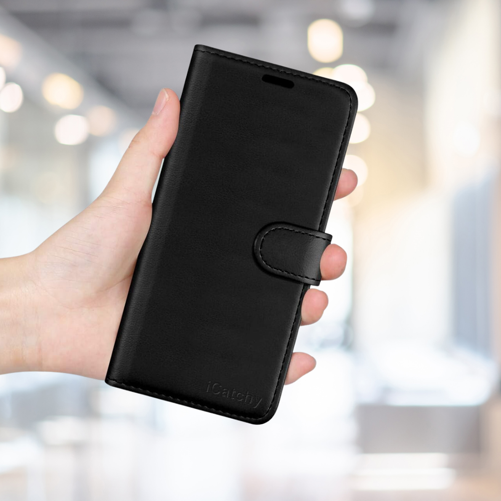 Bir el, tokalı kapaklı siyah deri telefon kılıfı tutuyor. Arka plan bulanık.