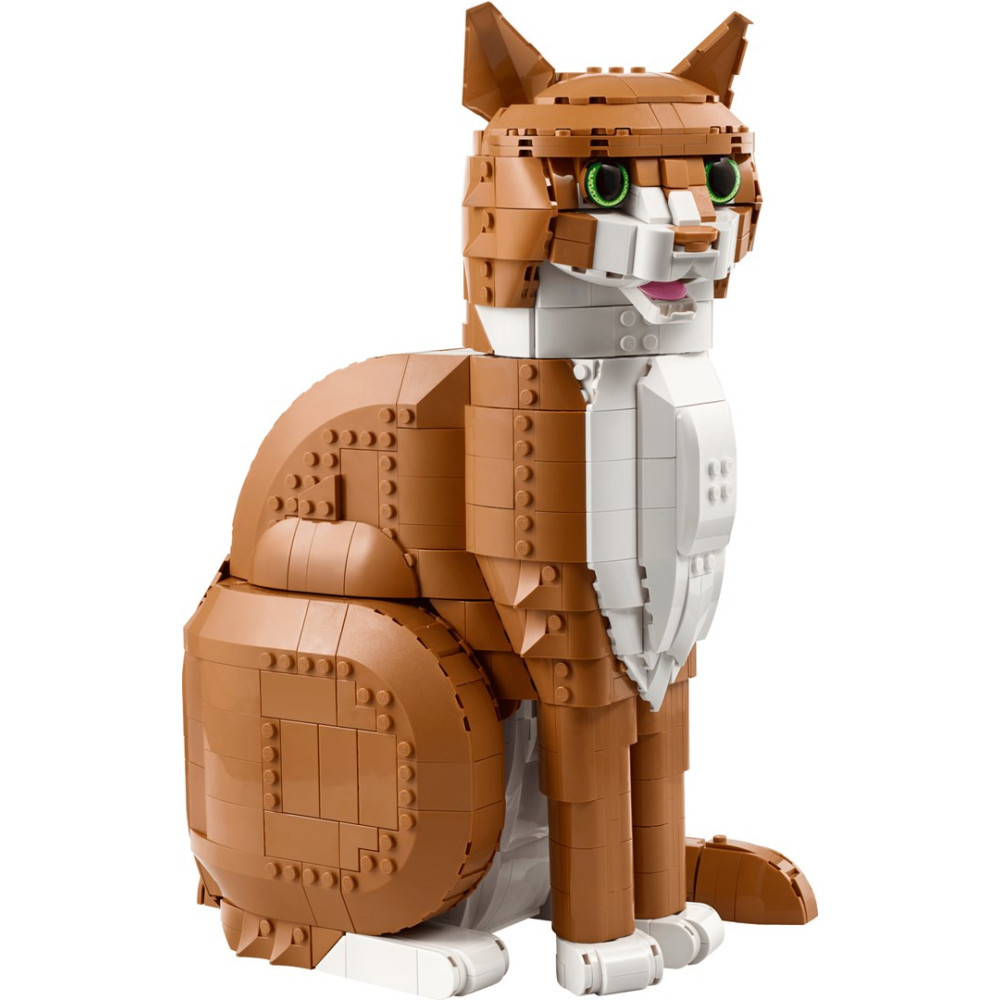 Brązowy i biały kot z Lego siedzi, patrząc do przodu, z zielonymi oczami i różowym językiem.