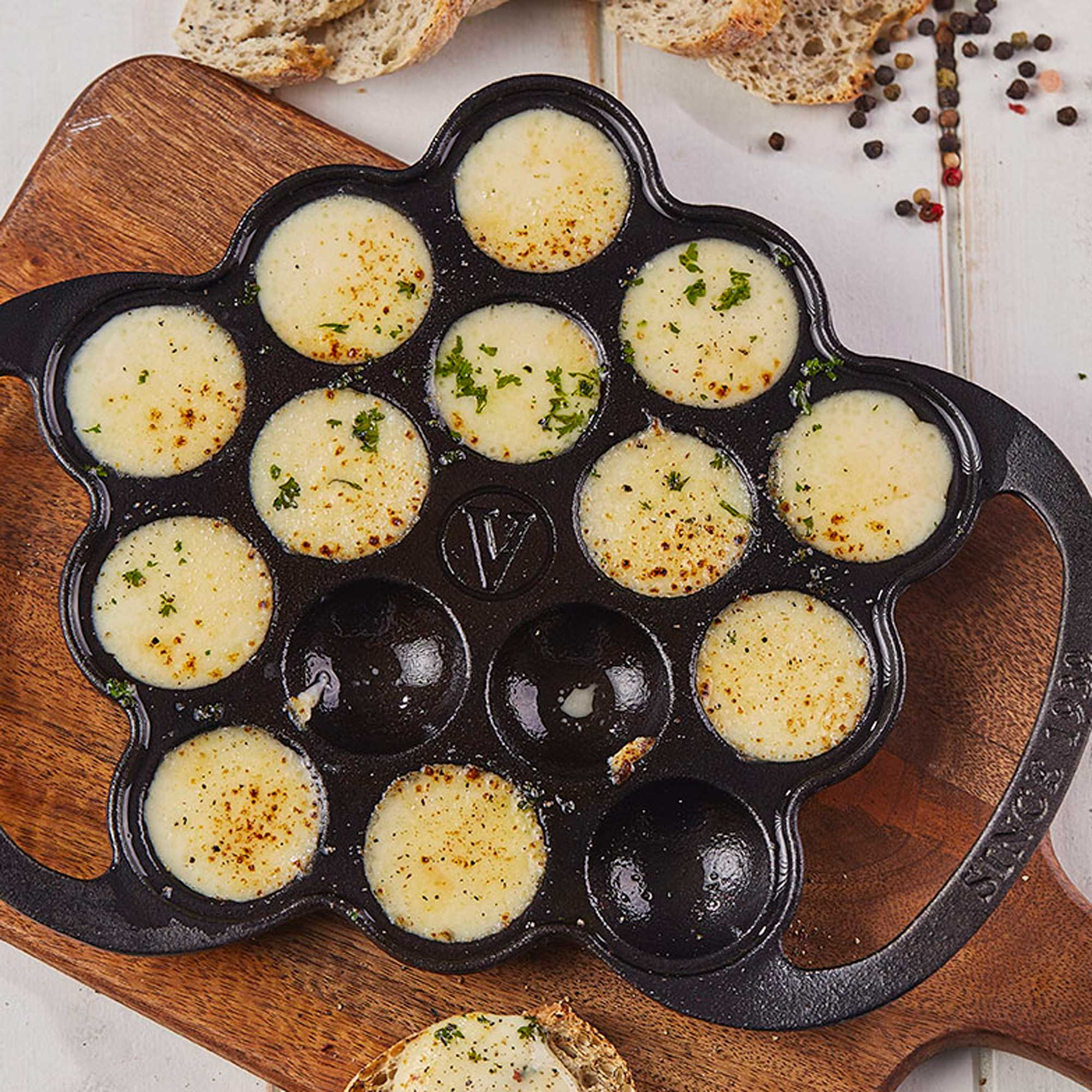 Ein Blumen-förmiger Gusseisen-Pfanne mit geschmolzenem Käse, garniert mit Petersilie.
