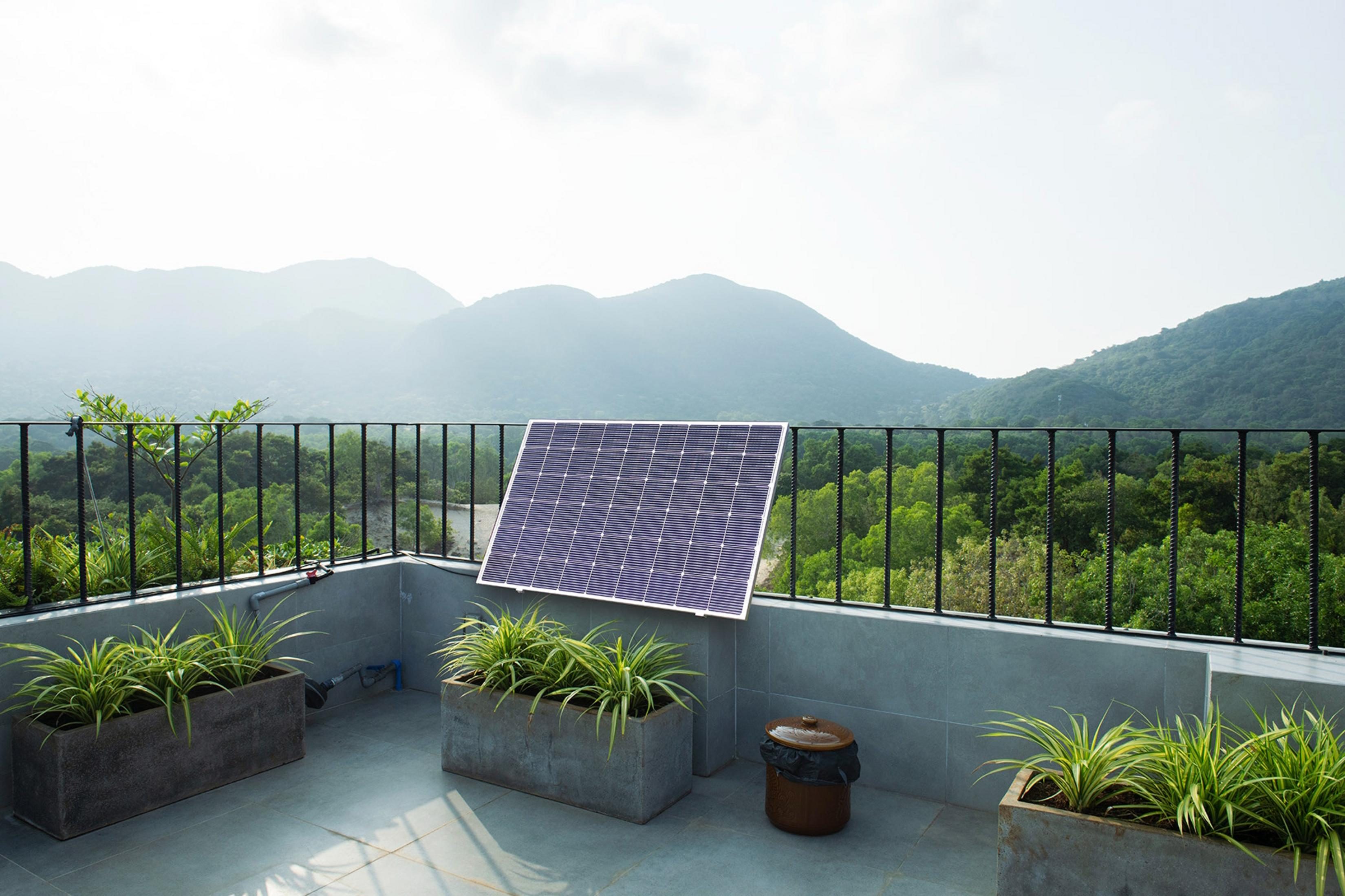 Un pannello solare si trova su una terrazza che domina montagne verdi.