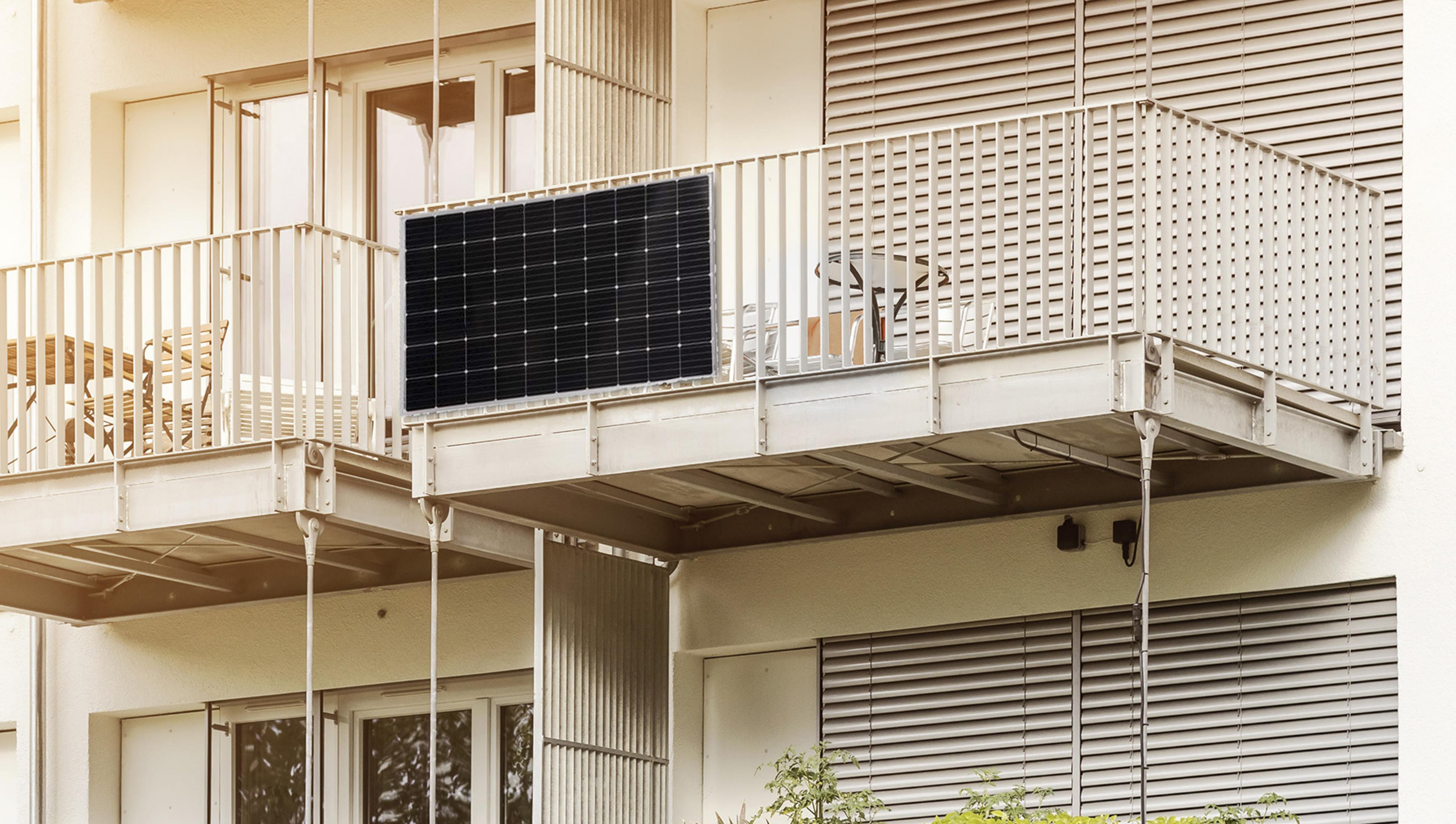 Balcone con pannello solare, tavolo e sedie di fronte a un edificio con persiane.
