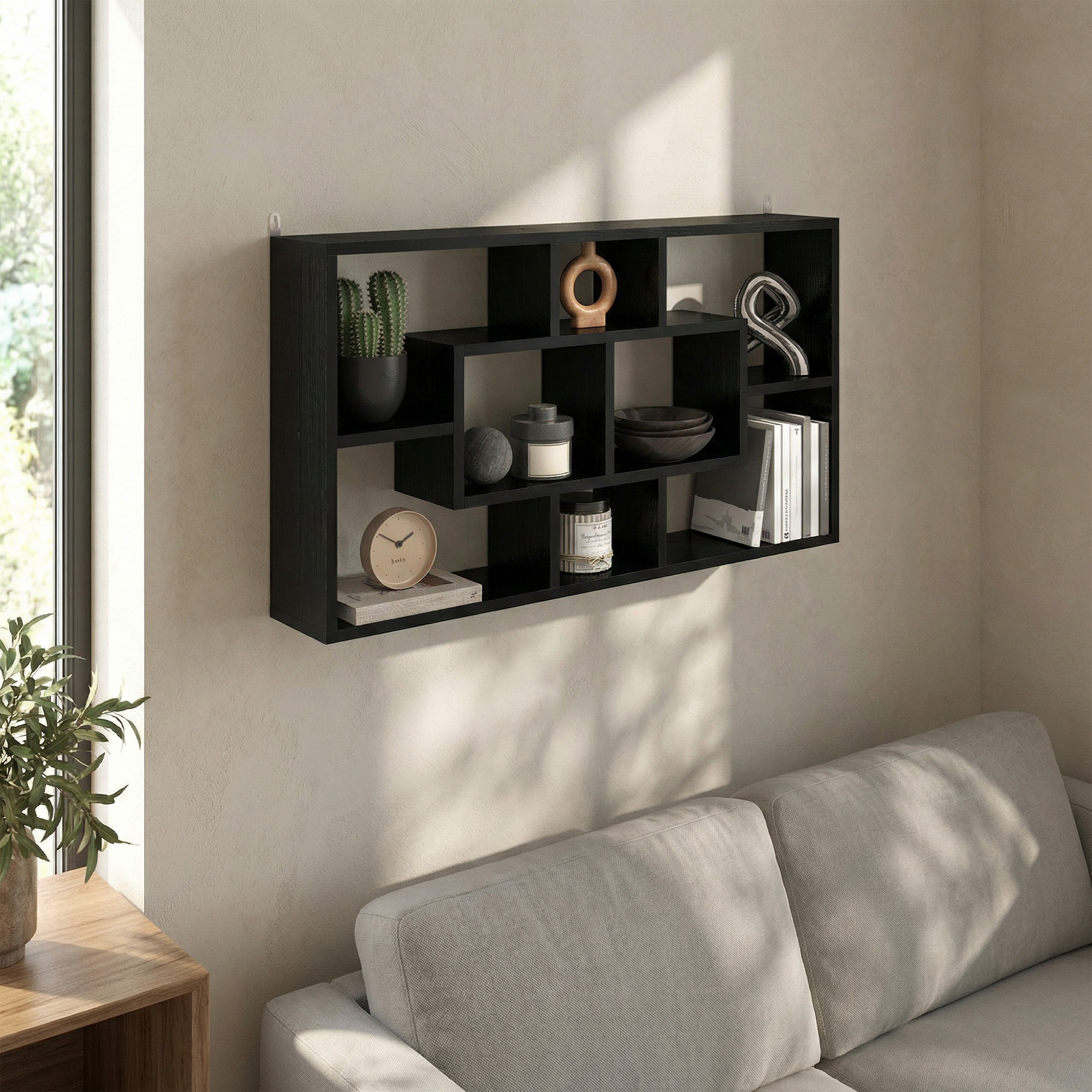 Una estantería negra en la pared con varios objetos decorativos como cactus, jarrones y libros.