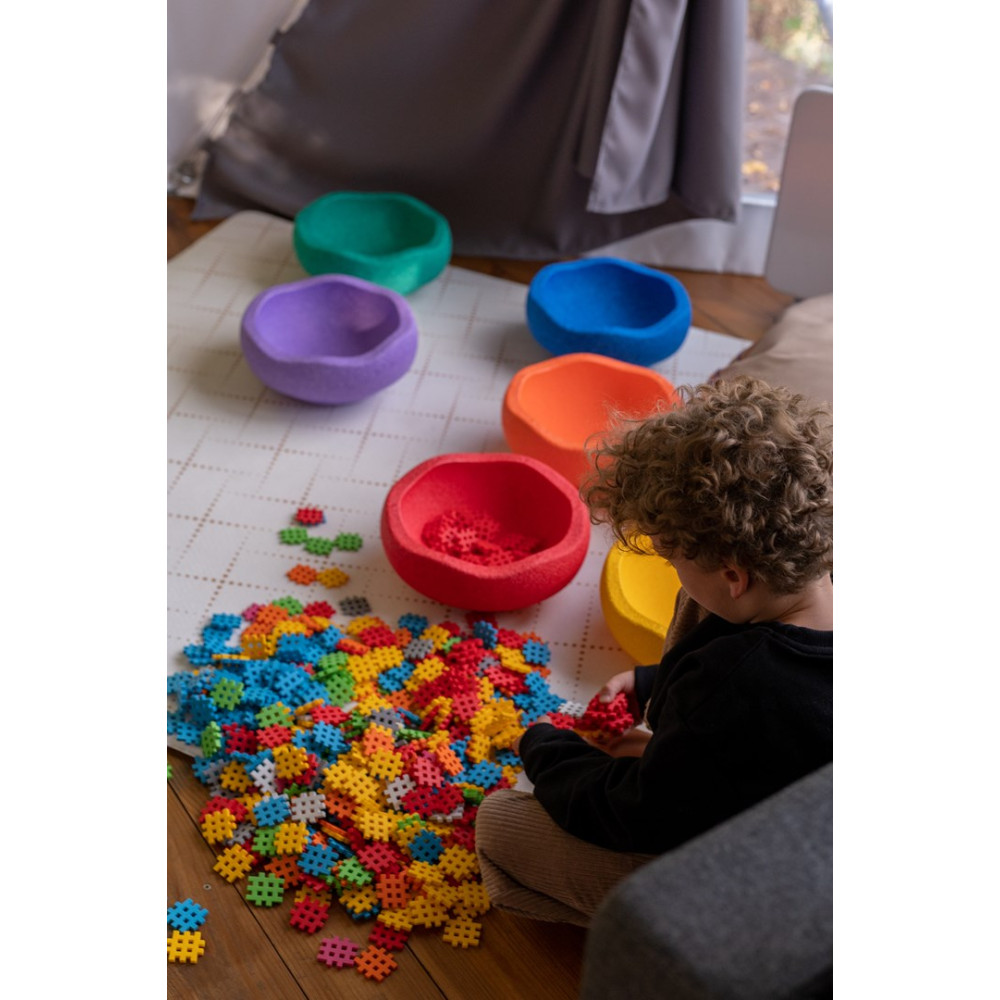 Un niño juega con bloques de construcción coloridos y cuencos coloridos.