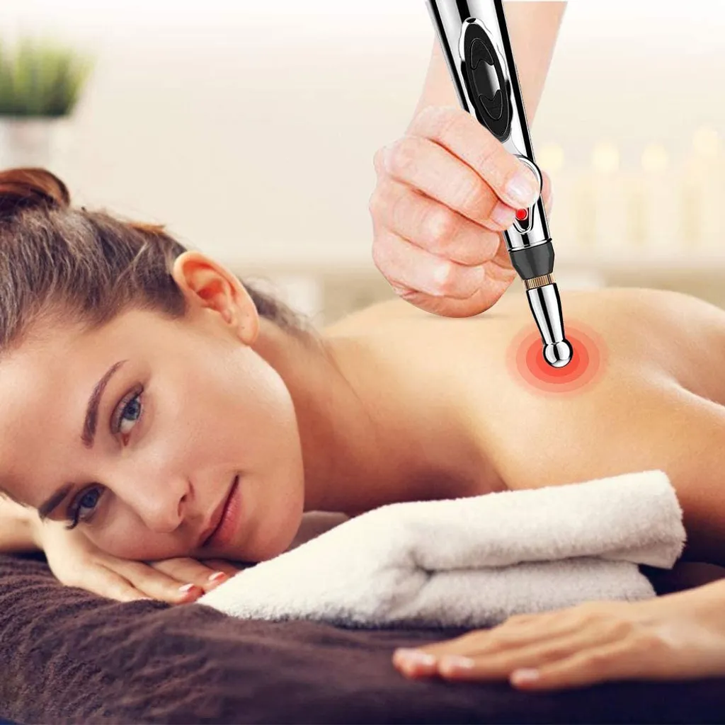 Eine Hand hält ein Massagegerät über den Rücken einer Frau, die auf einem Handtuch liegt.