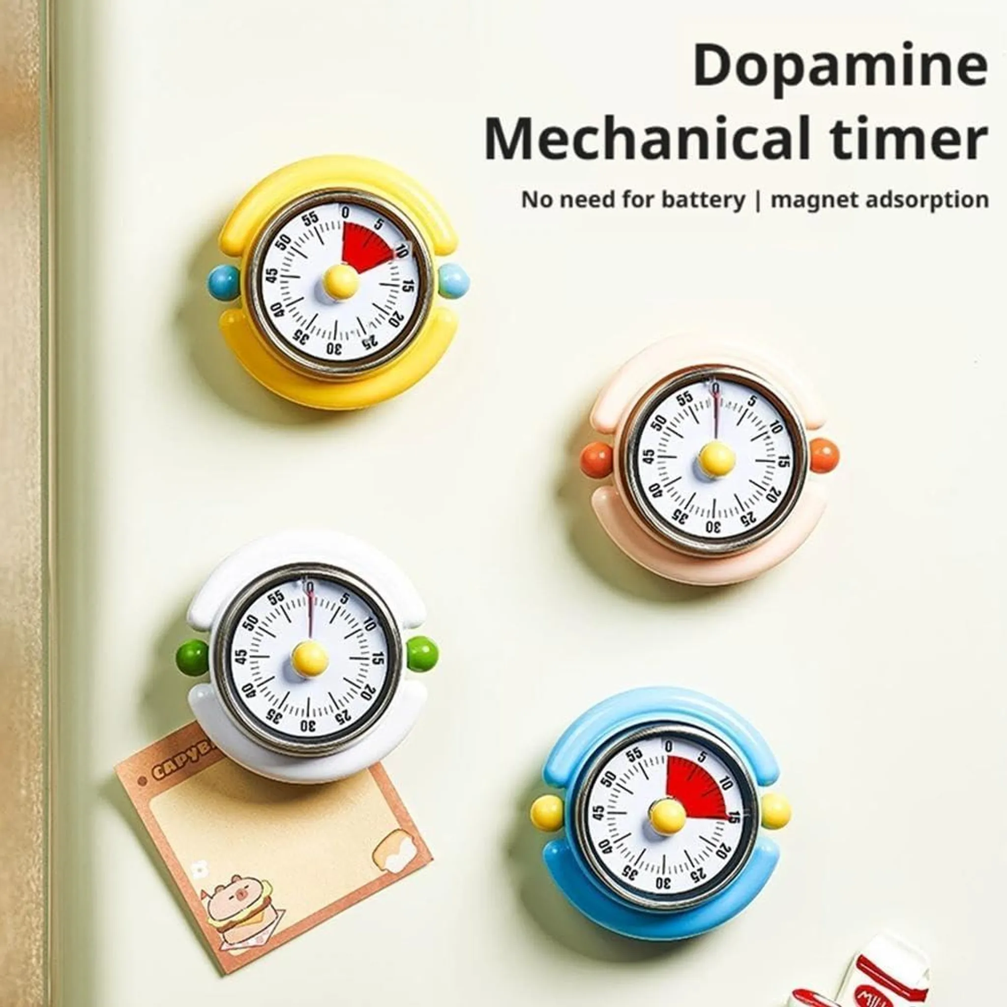 Vier mechanische Timer in Gelb, Rosa, Weiß und Blau auf einer weißen Oberfläche.