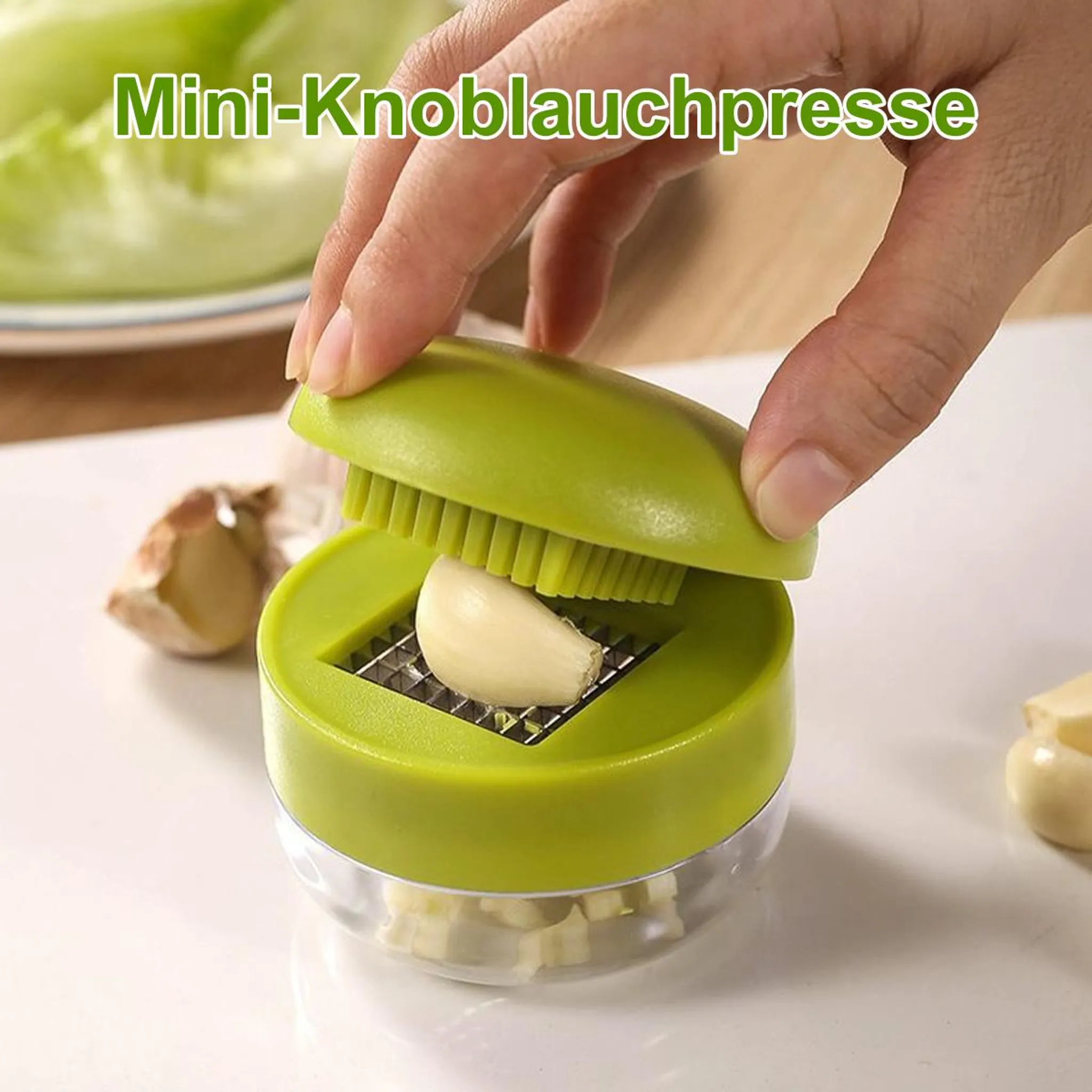 Grüne Knoblauchpresse mit einem Knoblauchzeh, der zerkleinert wird.