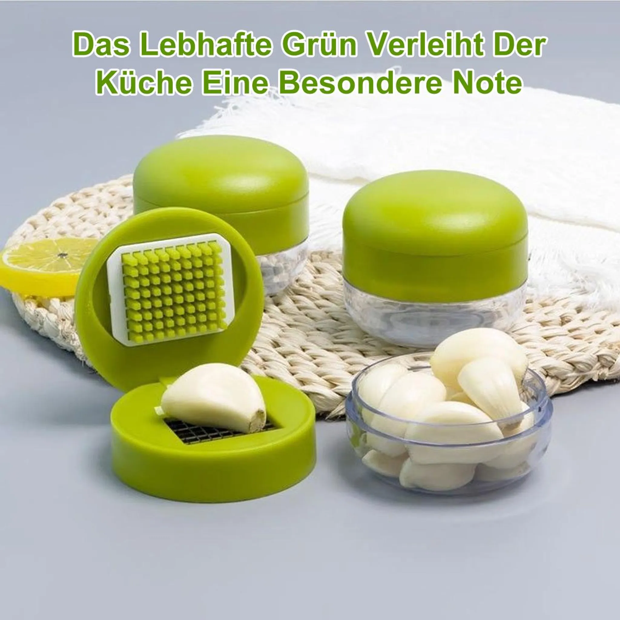Grüner Knoblauchschneider mit Knoblauchzehen und Zitronenscheibe.