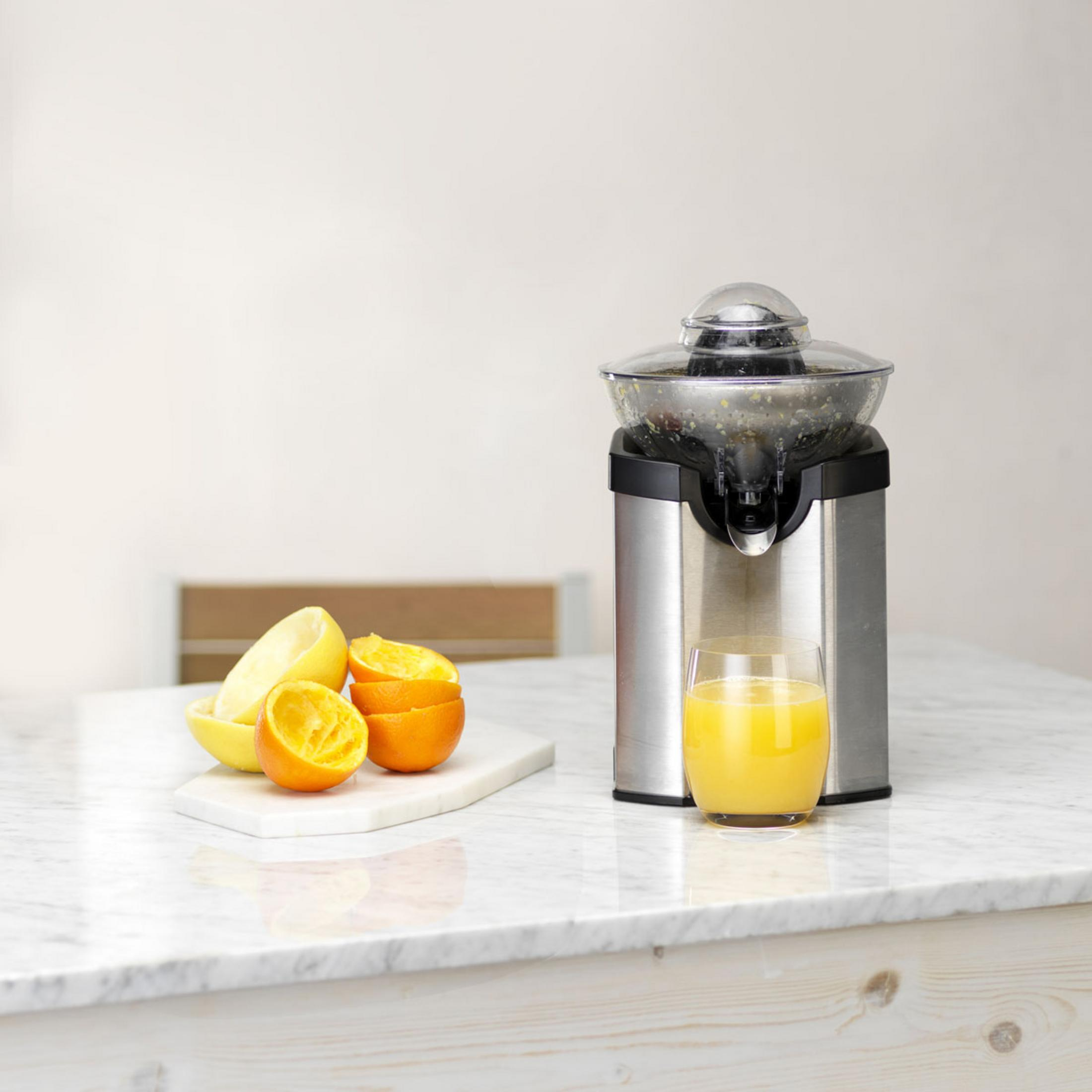 Ein elektrischer Entsafter mit Orangen- und Zitronenspalten und einem Glas Orangensaft.