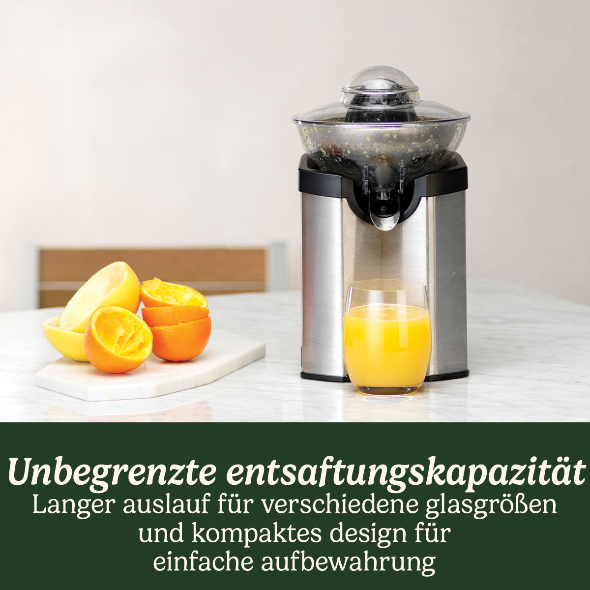 Edelstahlsaftpresse mit Glas Saft, Orangen und Zitronen auf Marmorplatte.