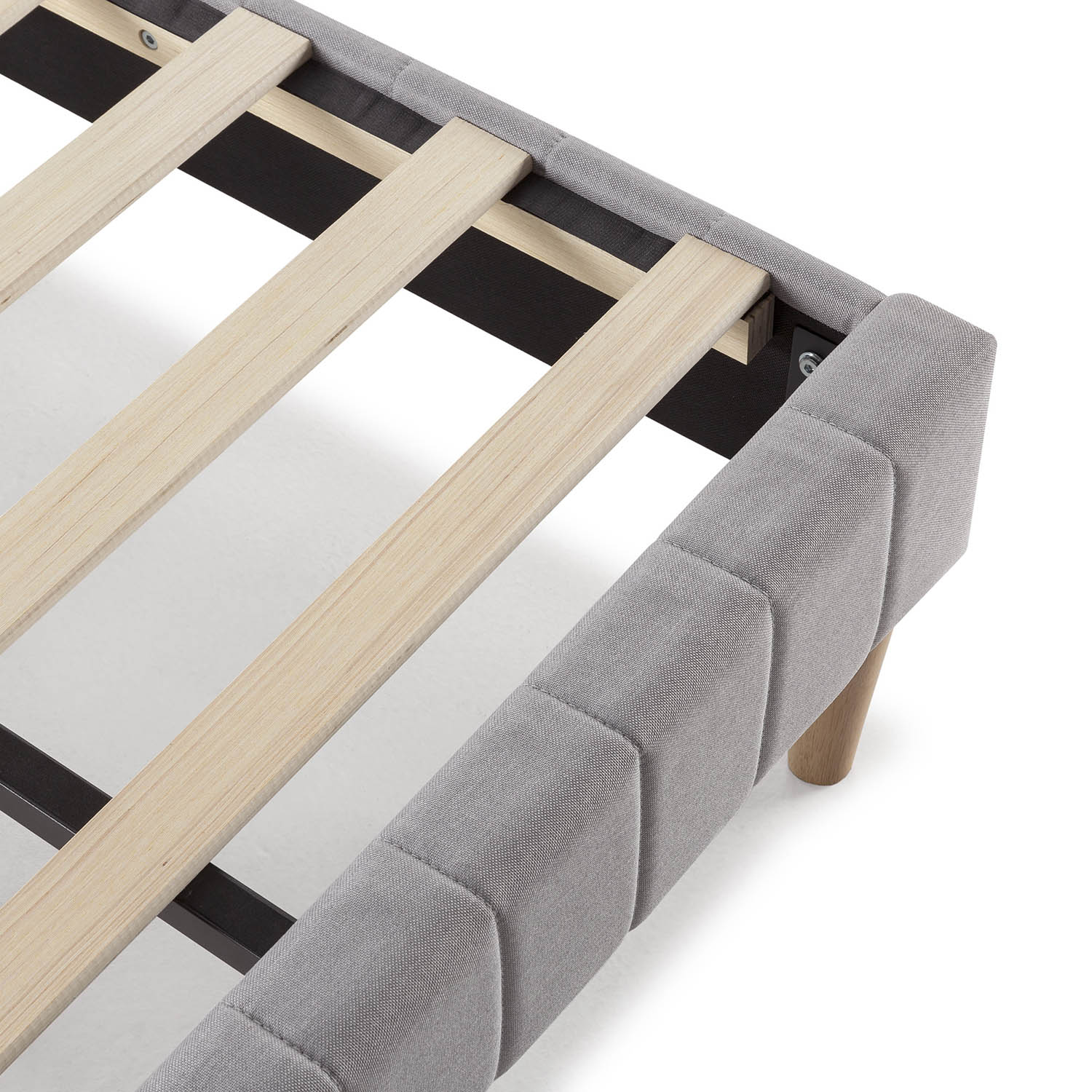 Marco de cama tapizado gris con listones de madera y patas sobre fondo blanco.
