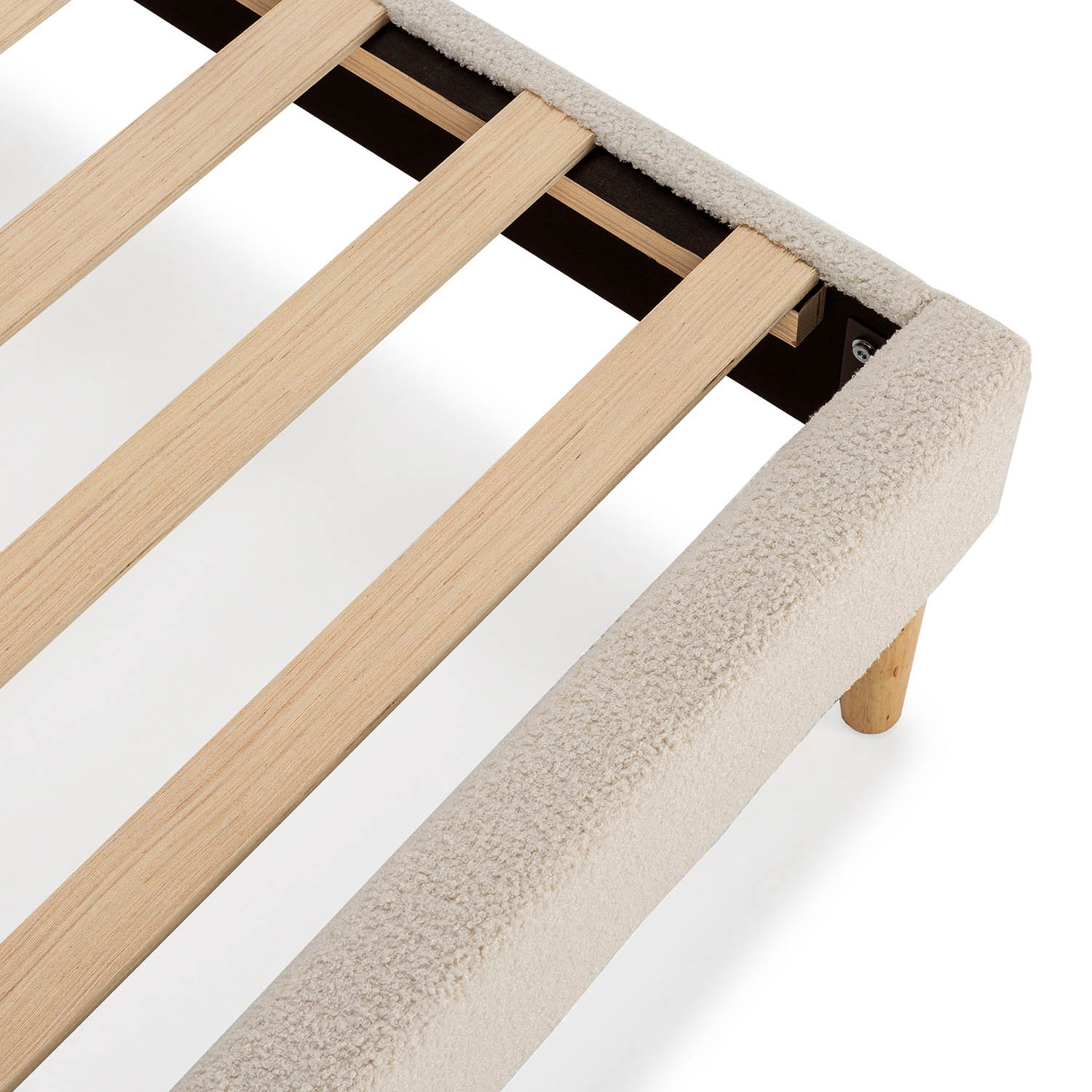 Primer plano de un somier claro y afelpado con listones y patas de madera.