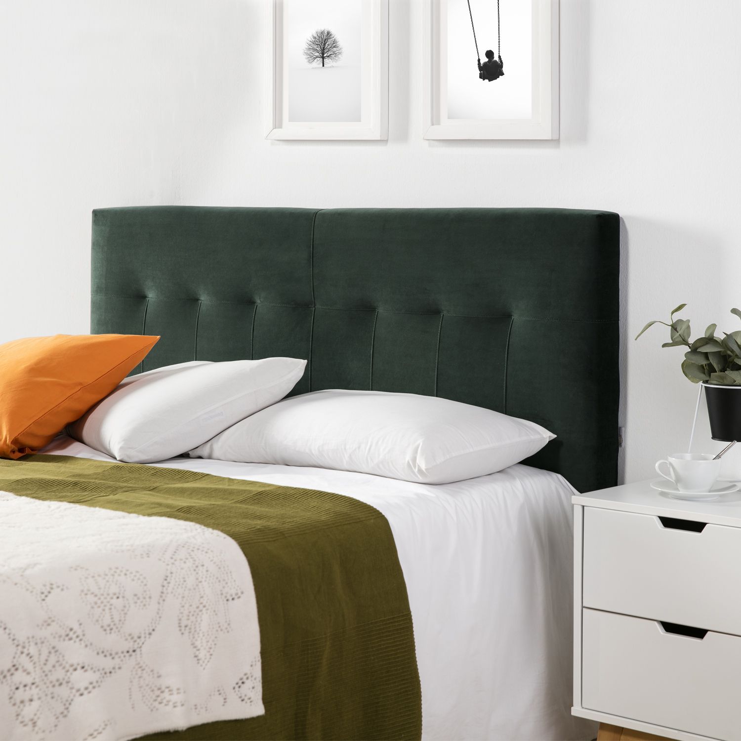 Un cabecero verde con cojines blancos y naranjas sobre una cama con sábanas blancas.